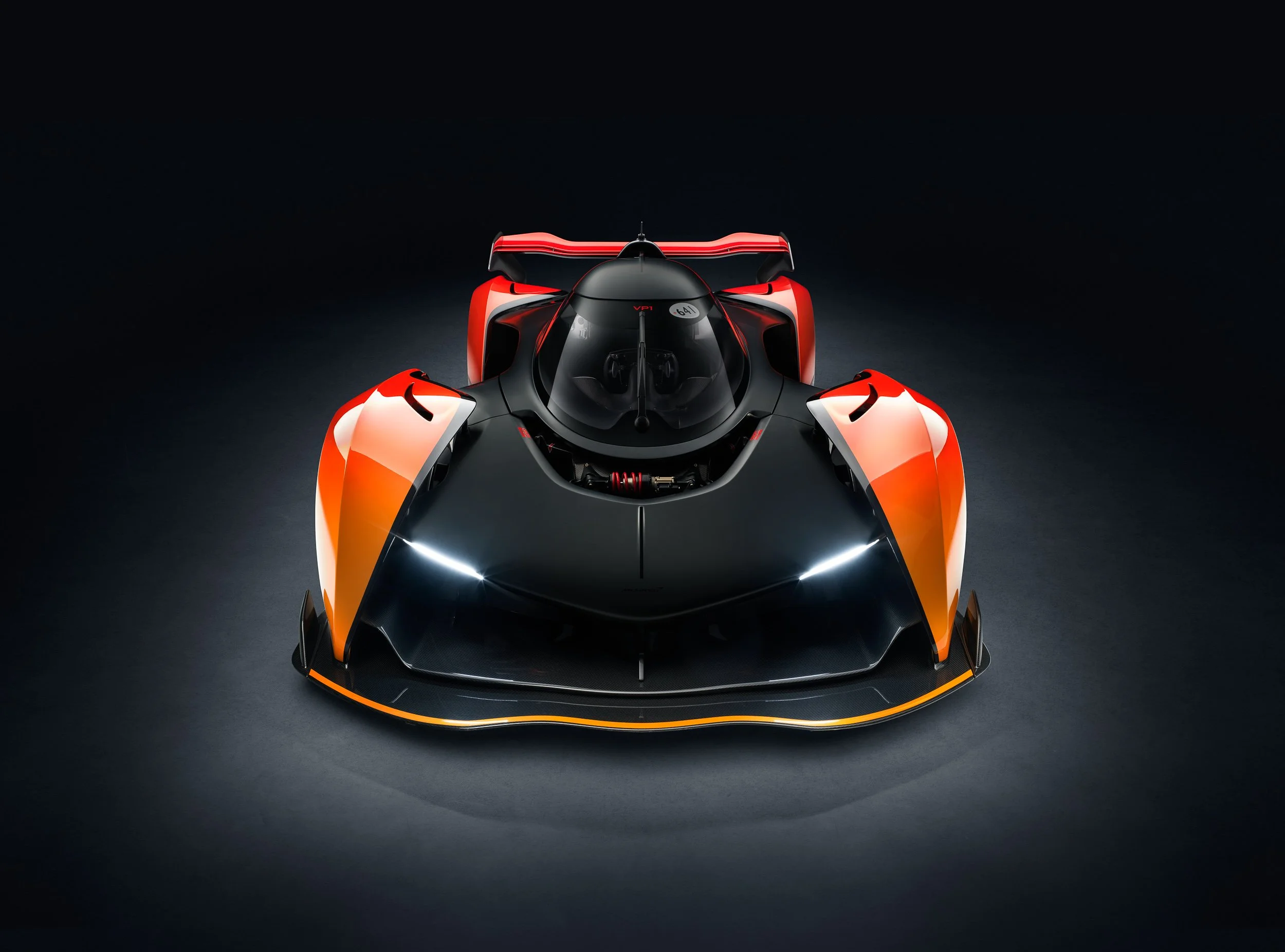 Top view of a futuristic orange and black hypercar with sleek aerodynamics and a large rear spoiler.