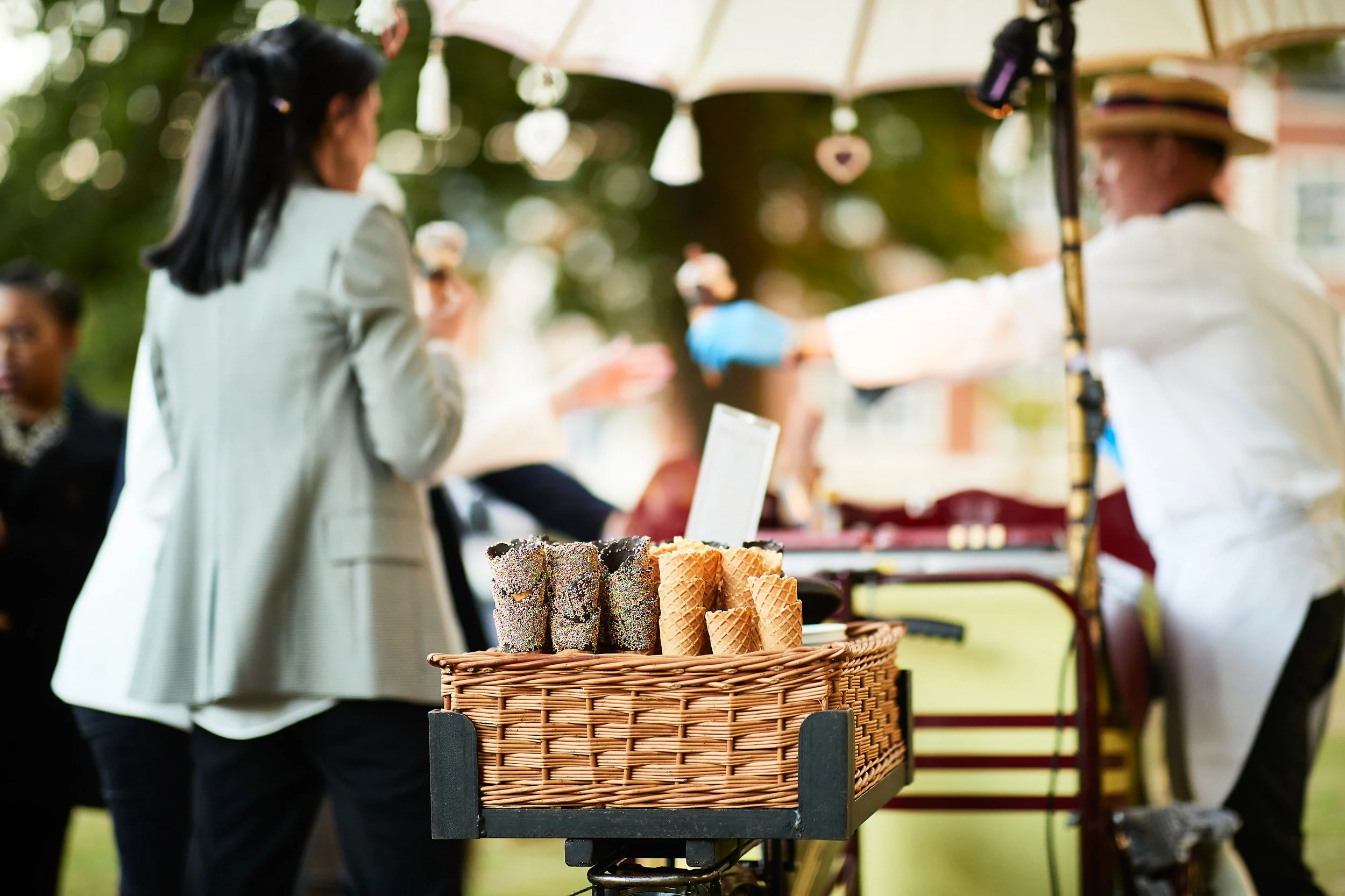 Ice cream vendor serving customers, with a basket of waffle cones in the foreground.