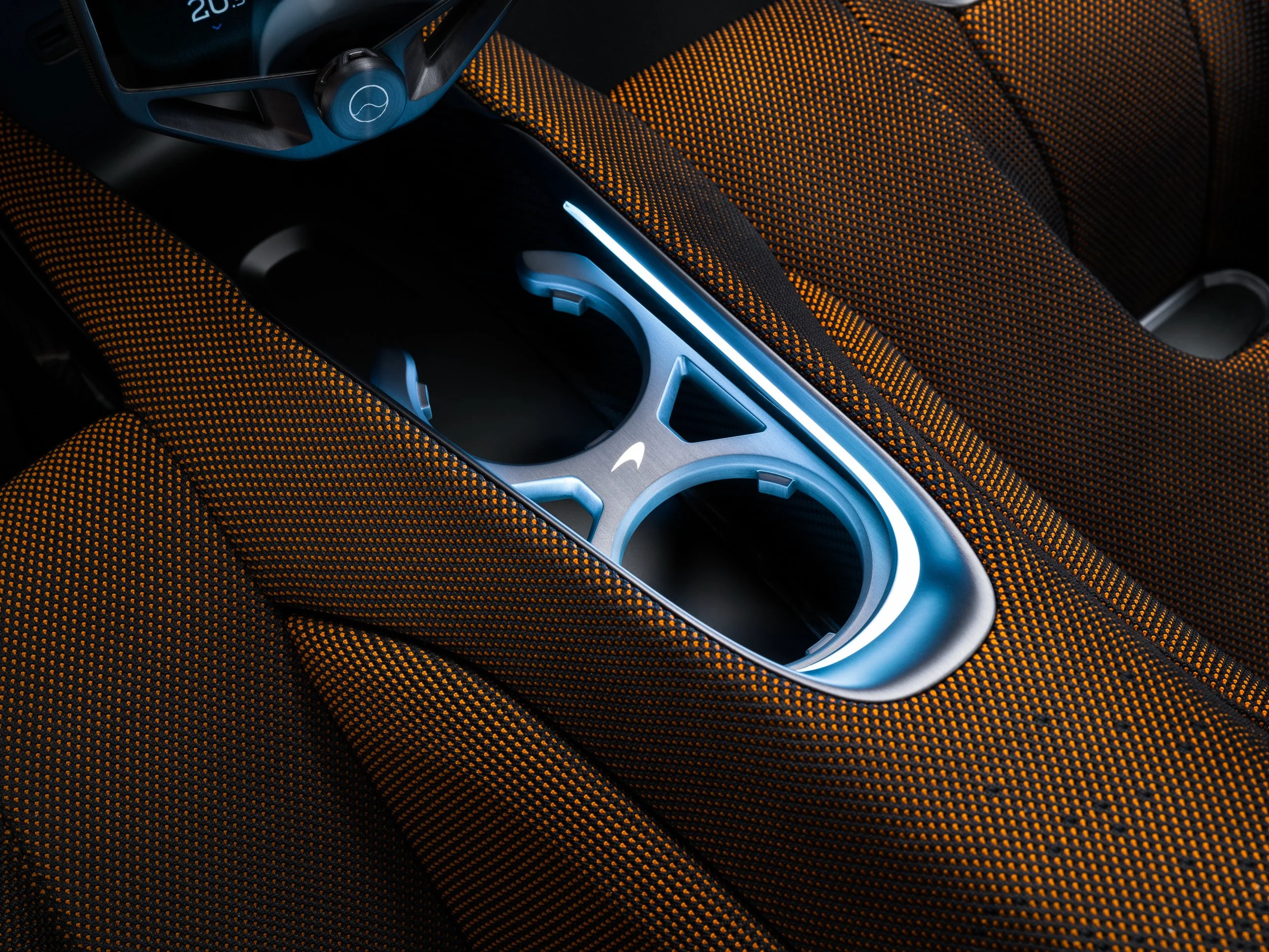 Close-up of a futuristic car interior with blue illuminated cup holders and textured orange upholstery.