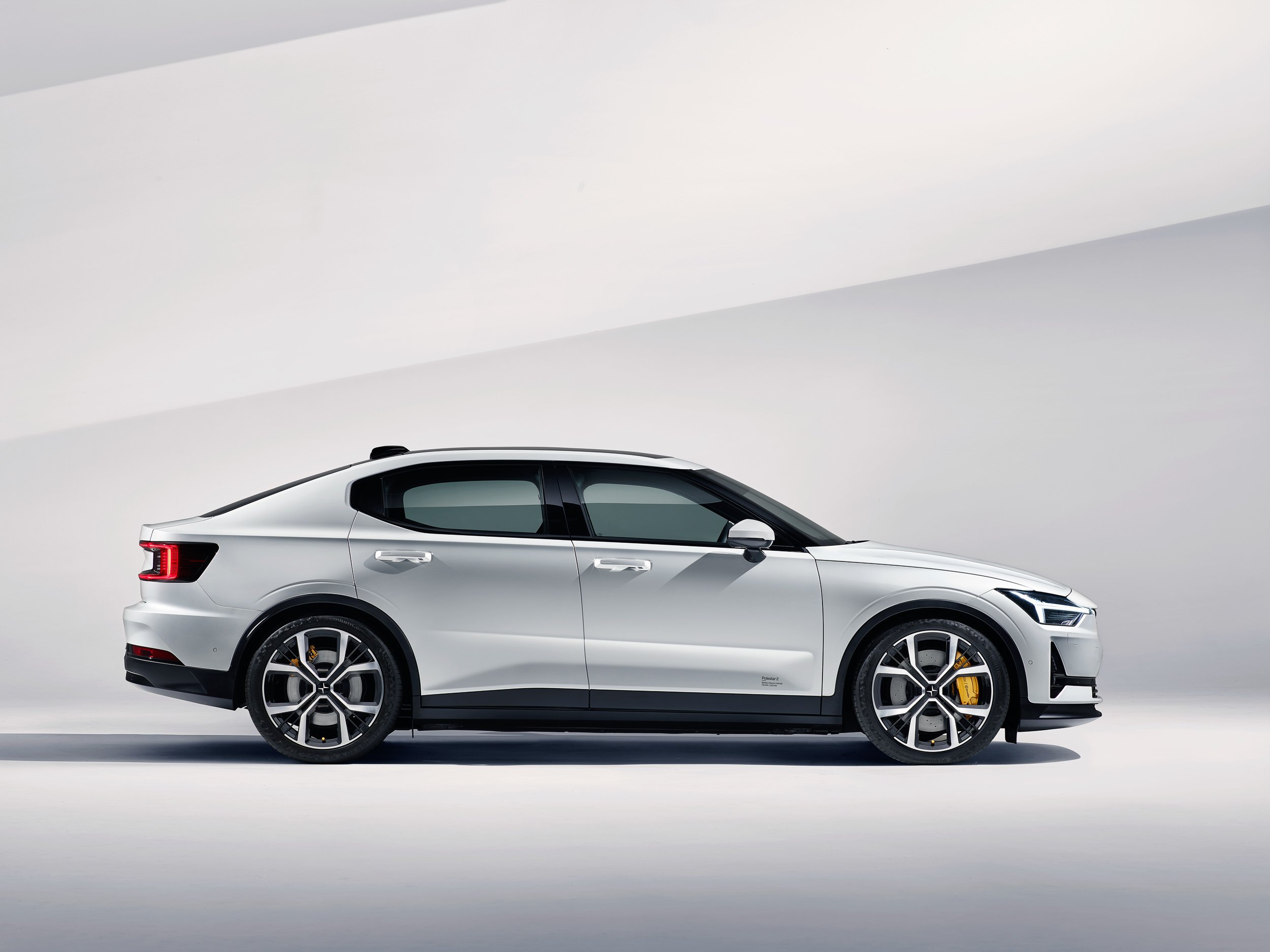 Side view of a white Polestar 2 electric car against a minimalist background.