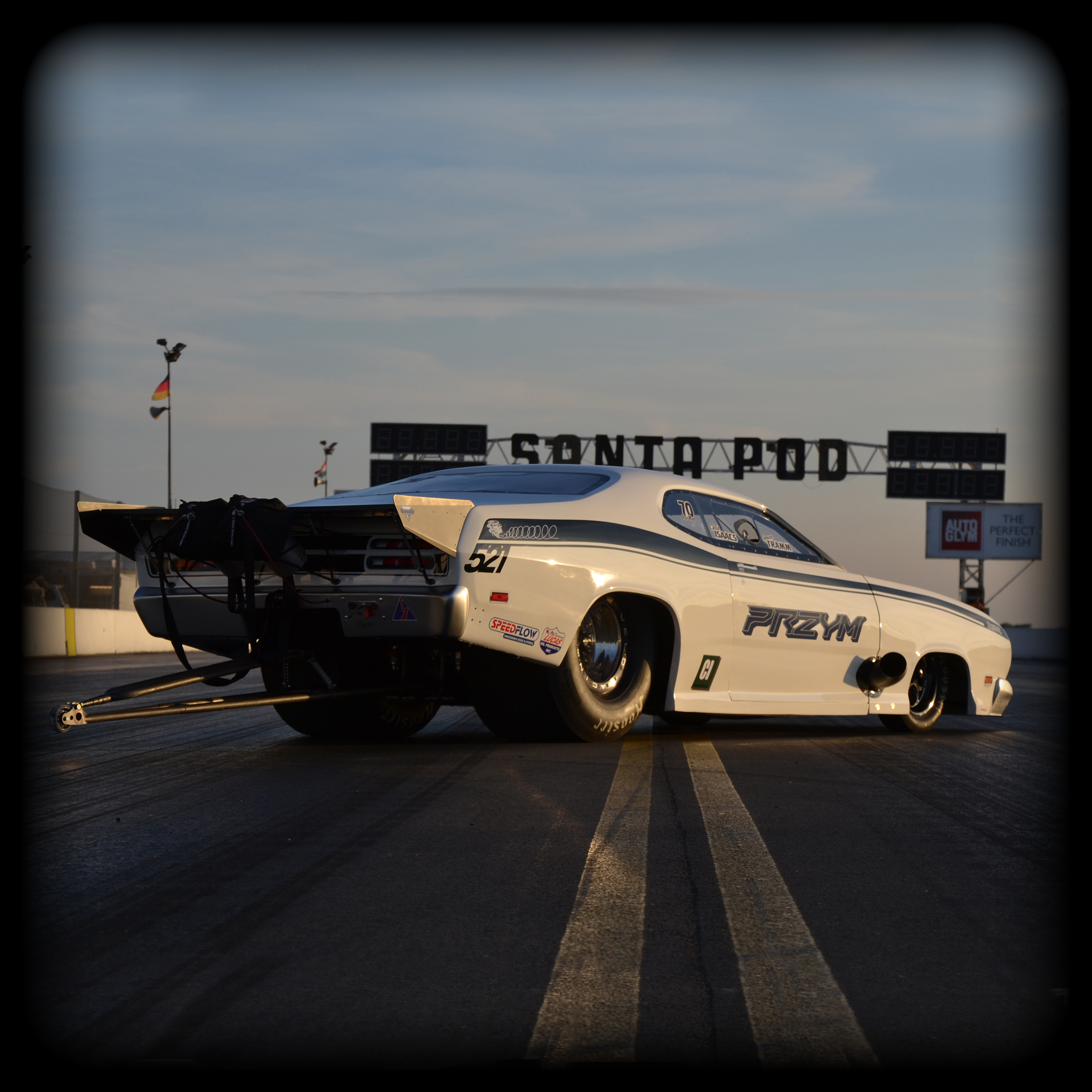 Plymouth Duster Pro mod Race car with racing decals on a racetrack at sunset.