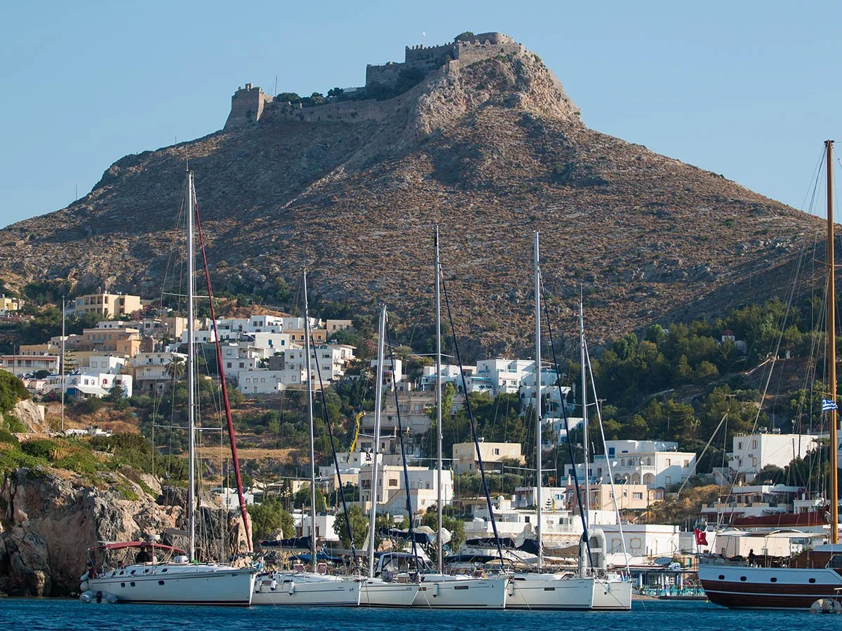 Sailing yachts moored in Leros, Greece, with the historic castle in the background. Professional yacht photographer in Greece providing commercial marine imaging across the Ionian and Dodecanese islands.