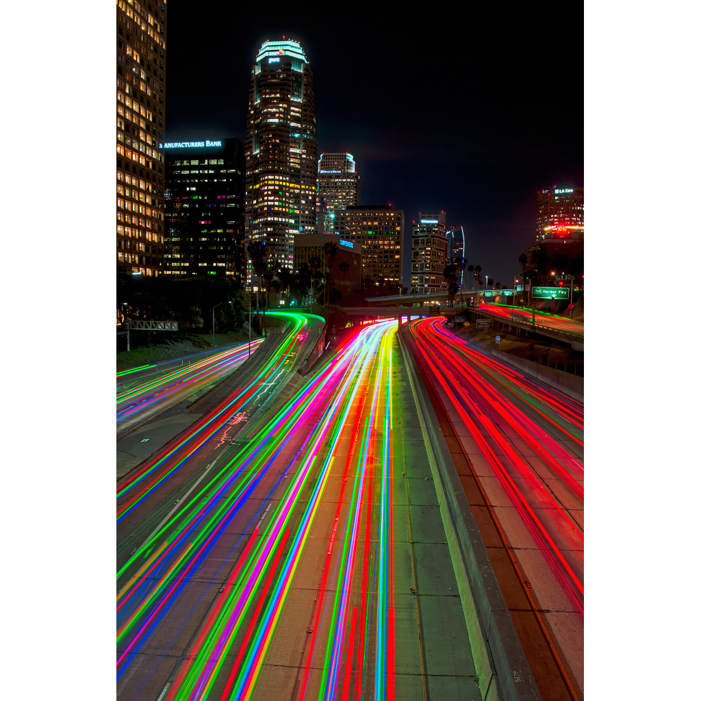 Downtown LA Lights – nighttime cityscape with vibrant multi-colored light trails on freeway and glowing skyscrapers in Los Angeles