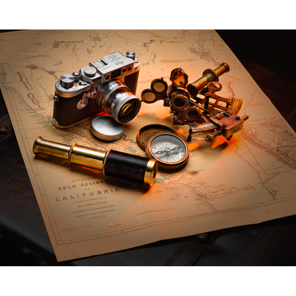 The Explorer’s Table – vintage Leica camera, brass sextant, compass and telescope on an antique California Gold Rush map