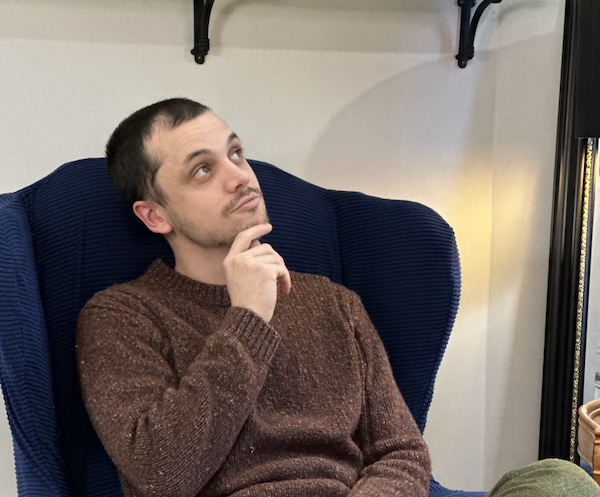 Photo of Izaak Lauer with hand on chin looking pensive up at the ceiling