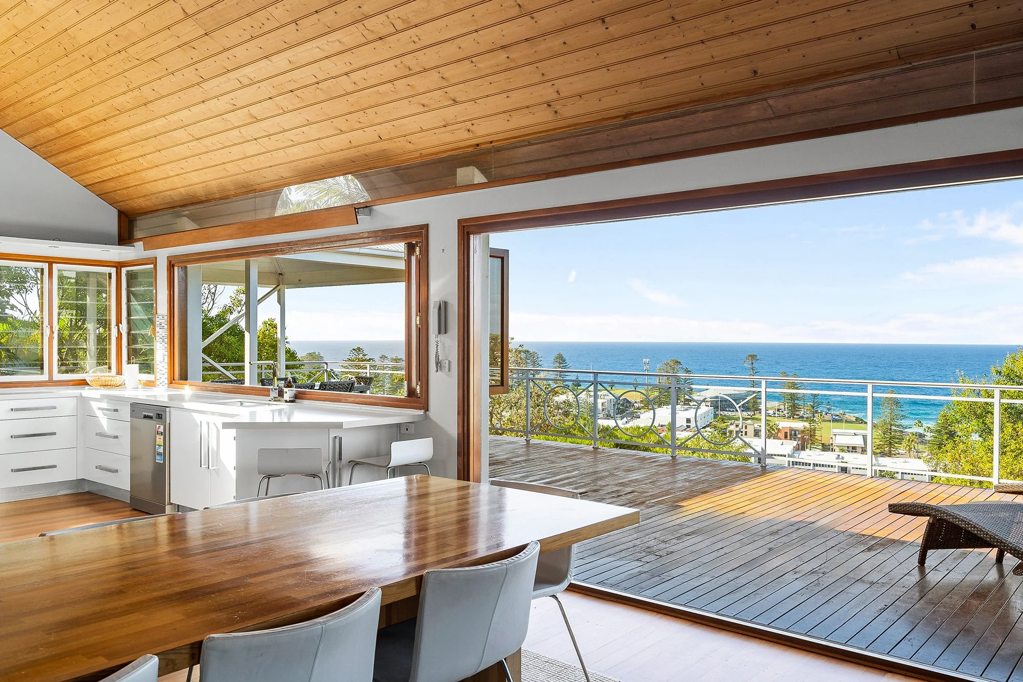 Interior image of a dining room and kitchen looking out towards an ocean view