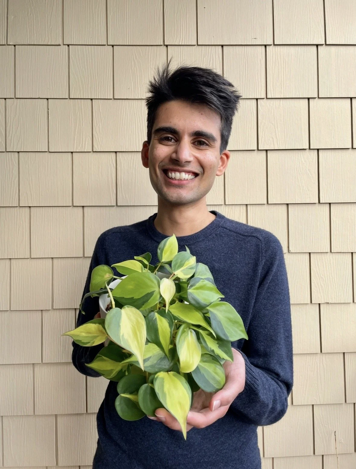 Hamza smiling with a potted plant