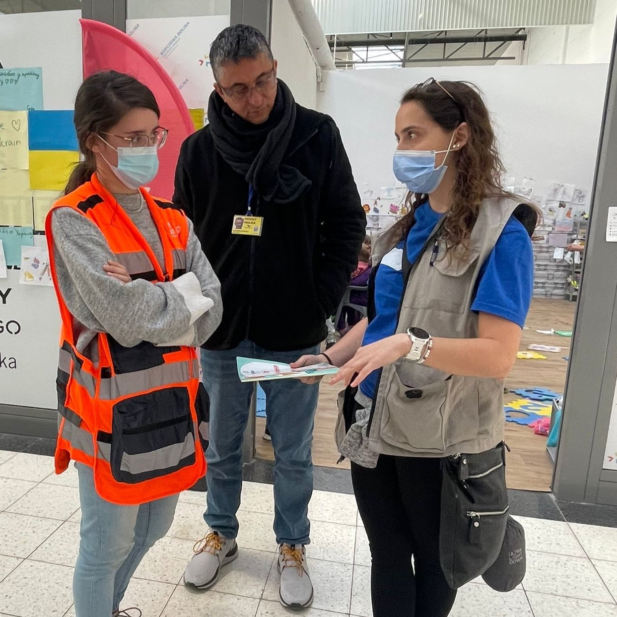 Cadena volunteer Andy Szydlo-Shein briefs NATAN social workers Tali Prilutski and Menny Malka at the Korczowa refugee center