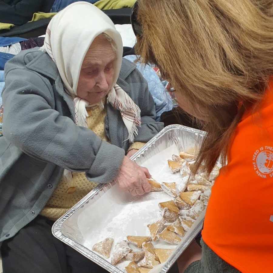 Passing out hamantaschen pastries at the refugee center Purim party