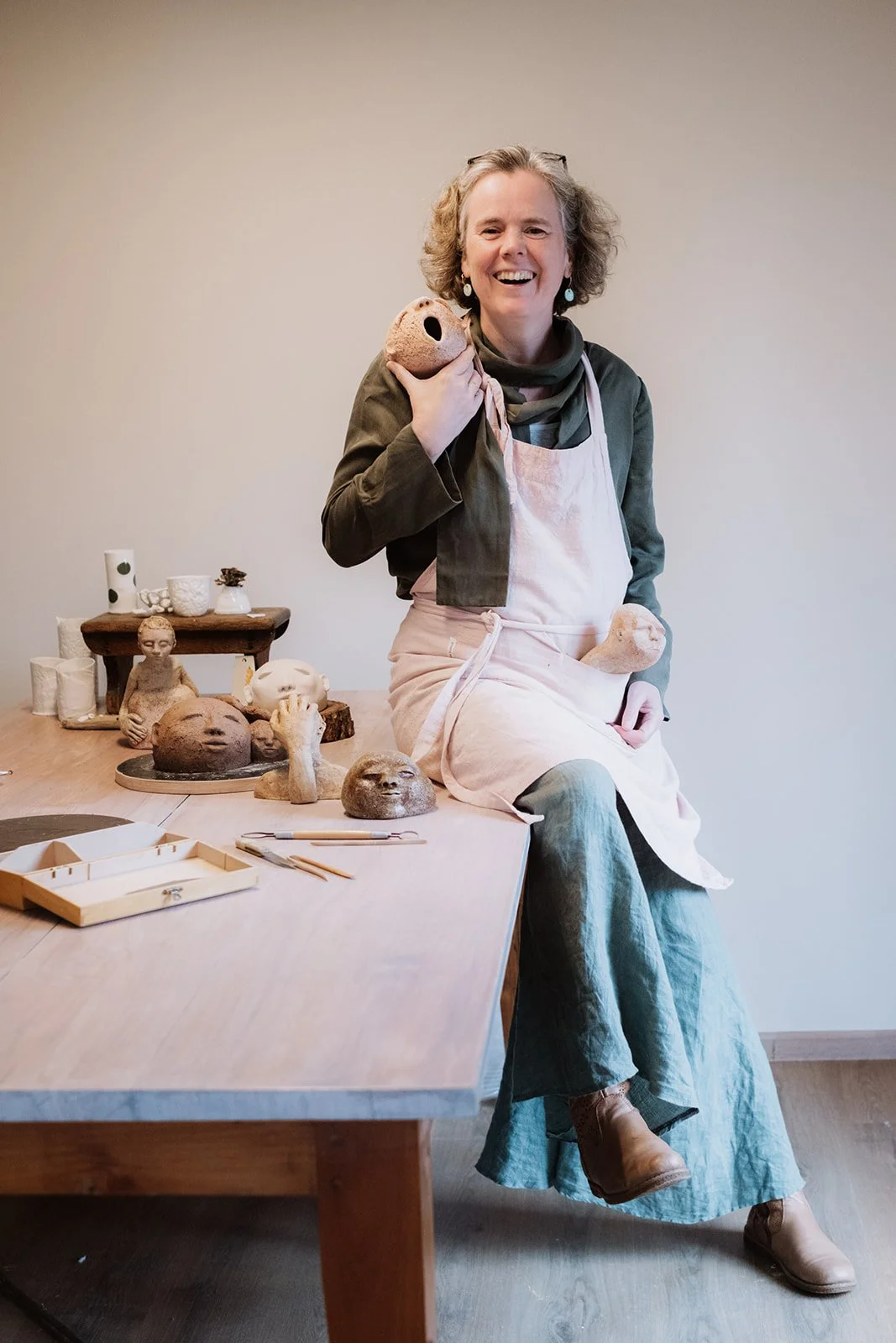 Heidi zit op de tafel omringd door het sculpturale keramiek