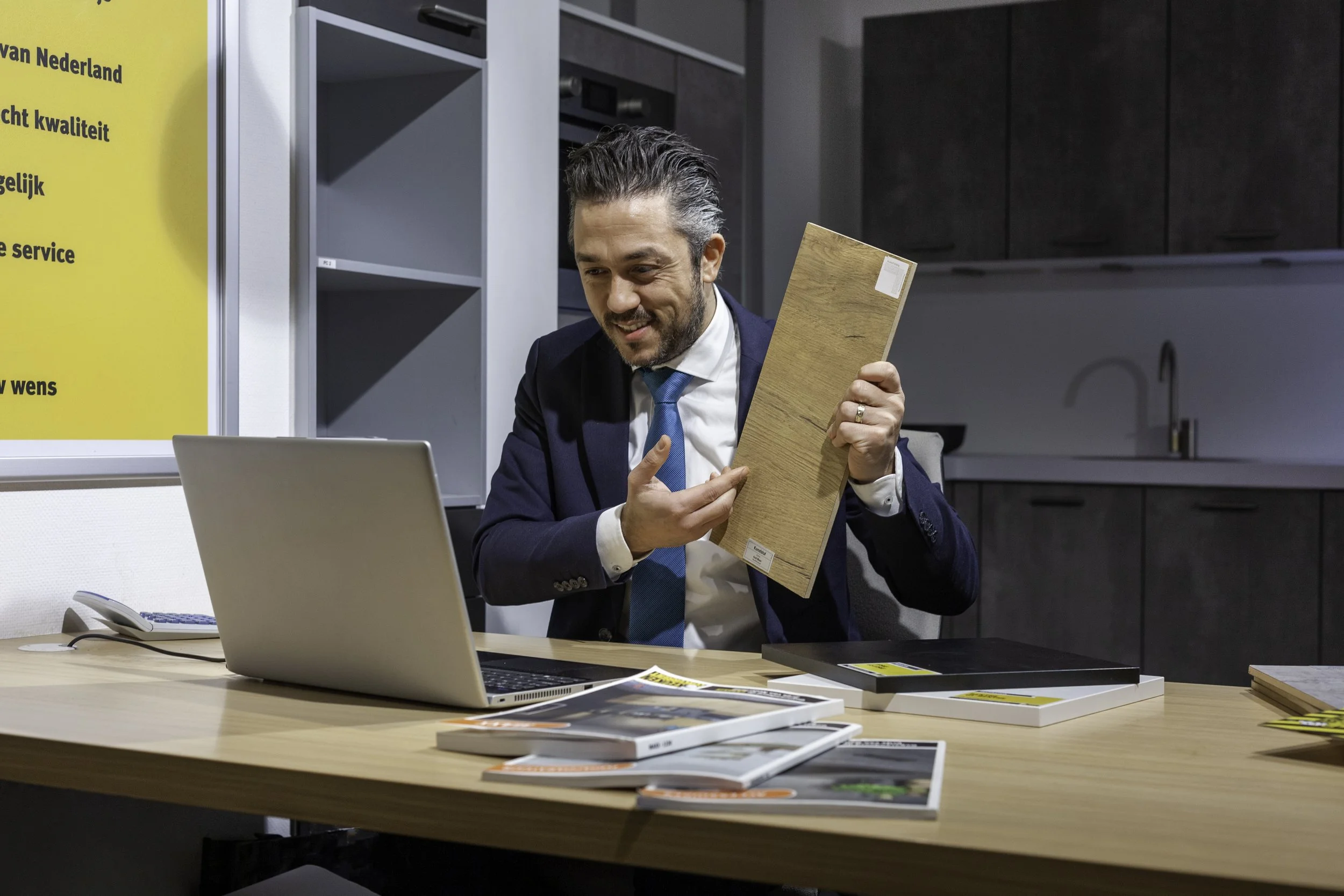 Man in businesspak koopt een houten vloerproef in een kantoor.