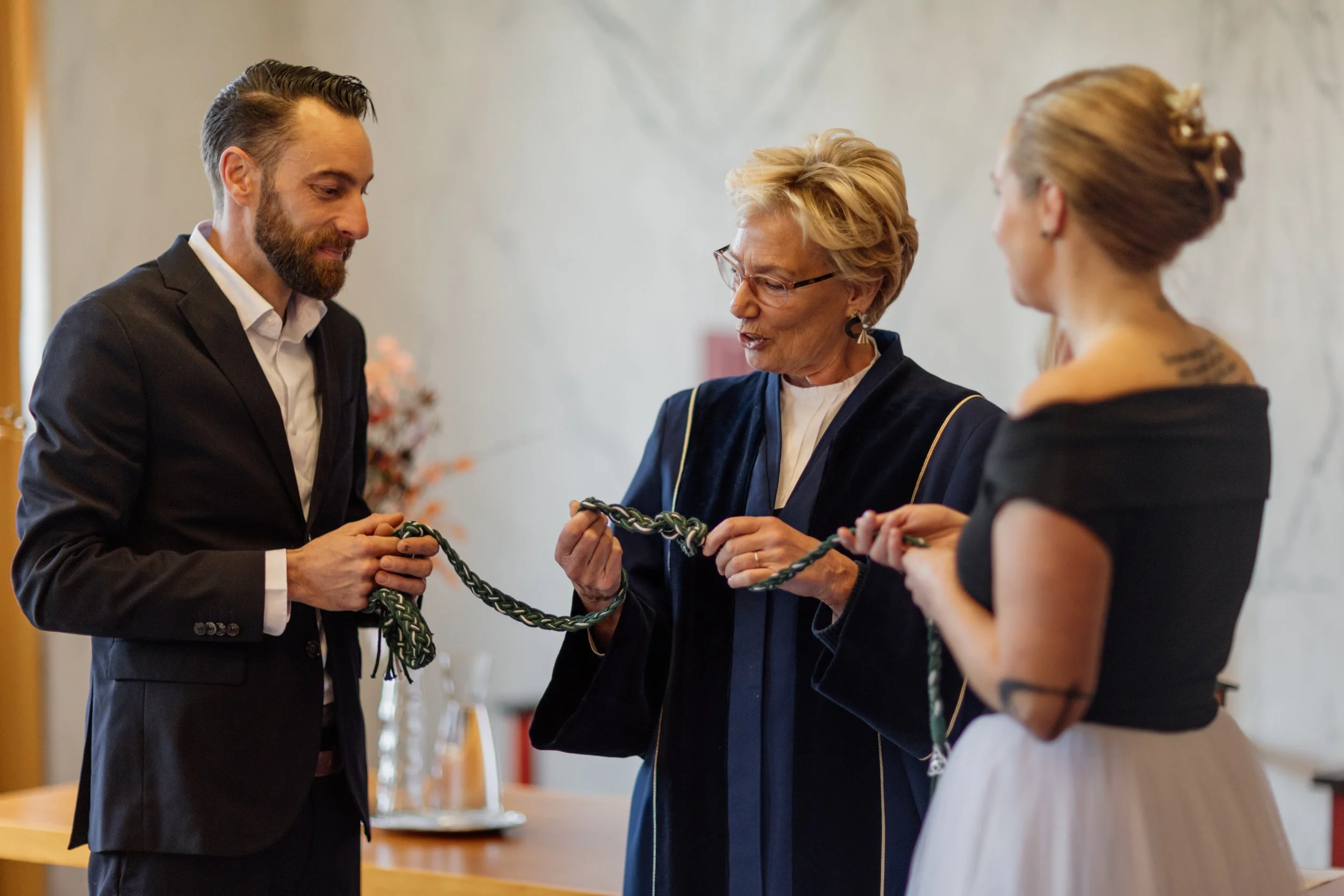 Dri mensen die een ceremonie houden en een geslepen ketting vasthouden.