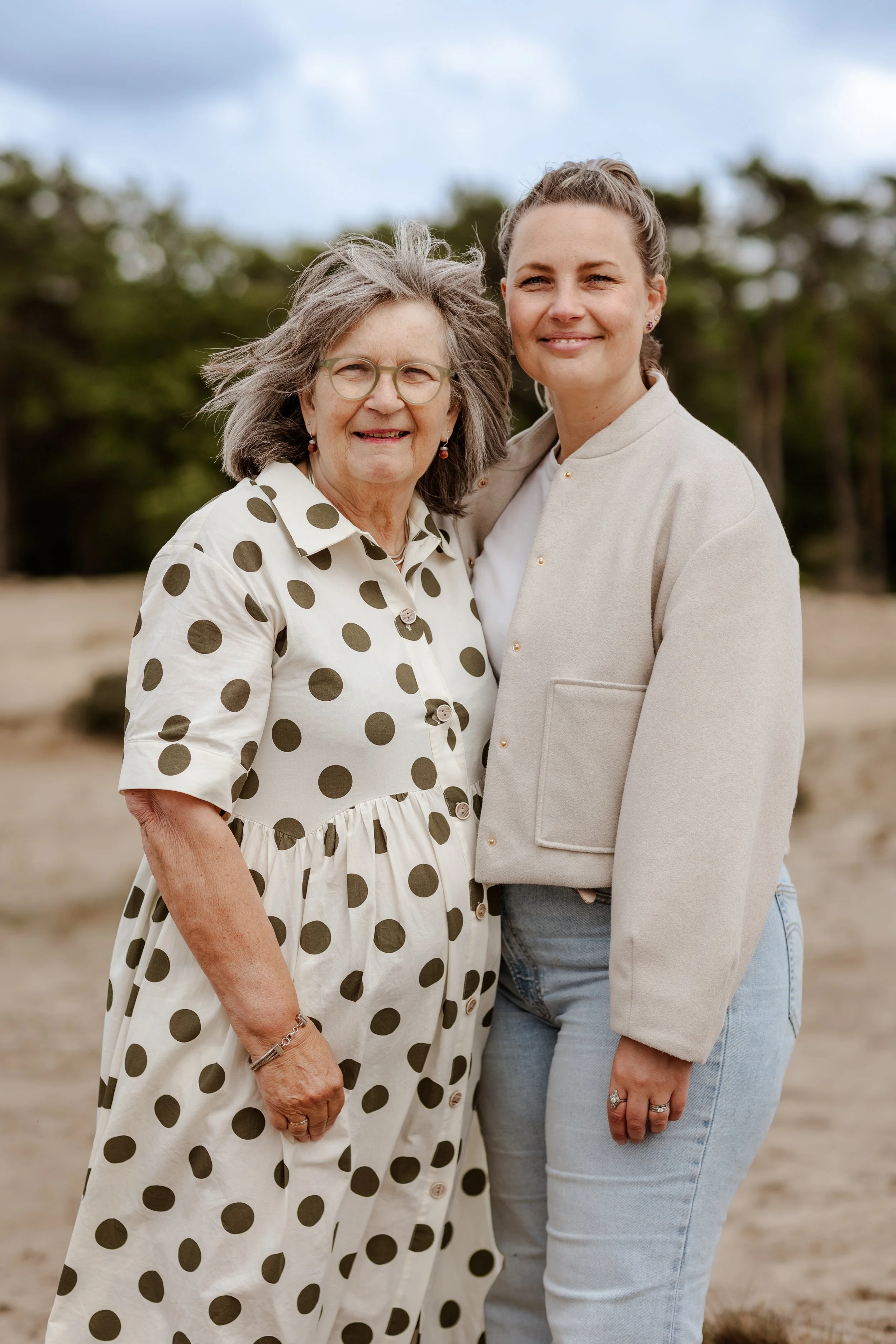 Twee vrouwen staan buiten in een natuurgebied, dicht bij elkaar, smiling.