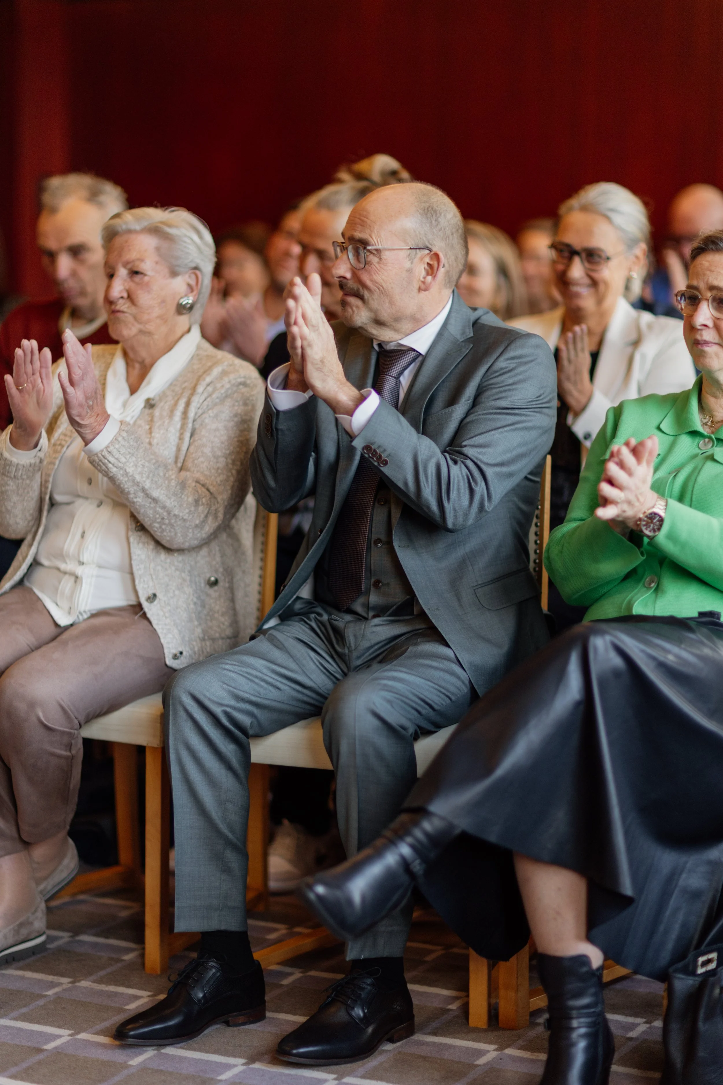 Mensen die applaudisseren tijdens een bijeenkomst of ceremonie in een zaal.