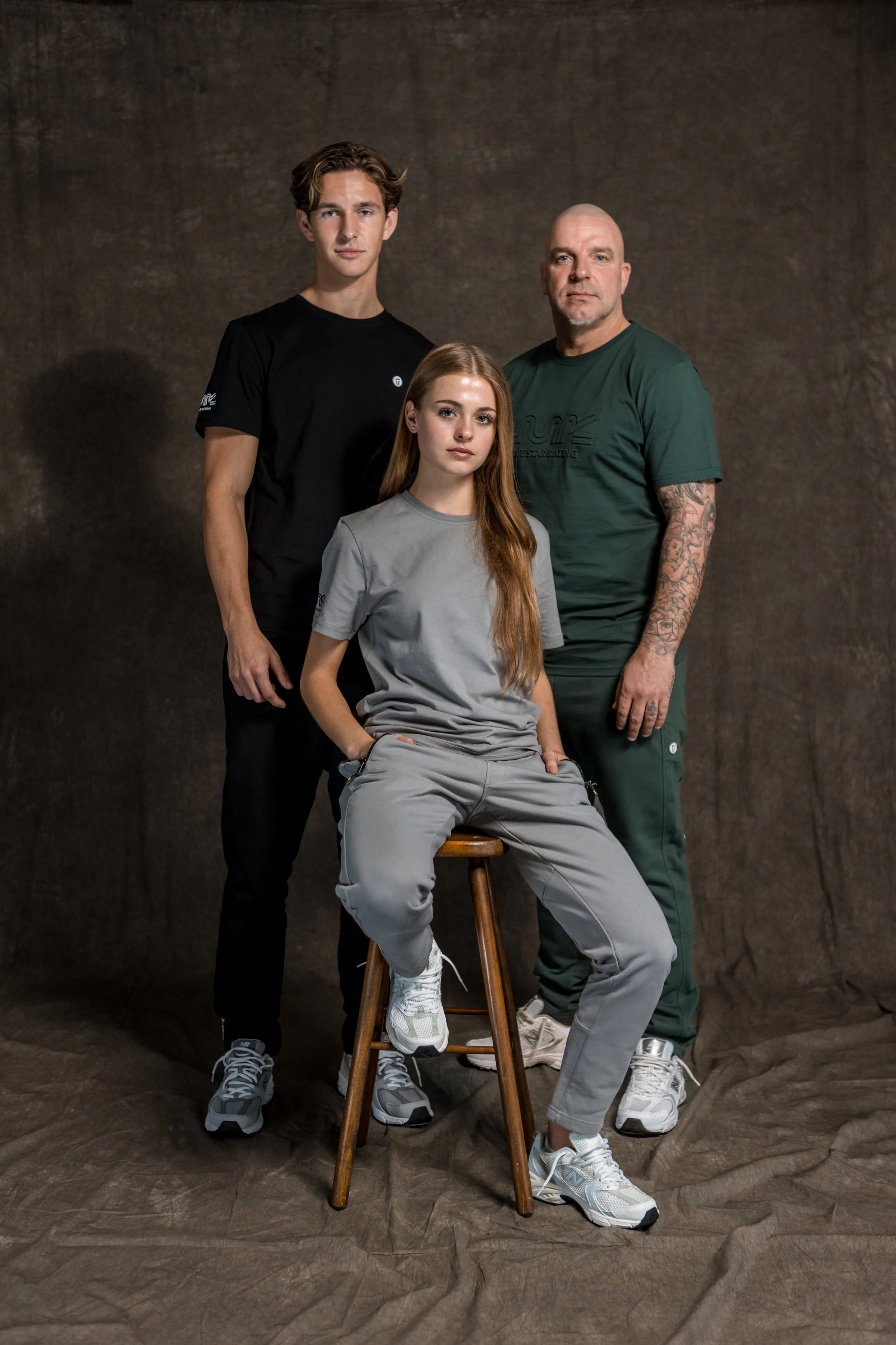 Dooie mensen en een jonge vrouw in casual kleding voor een effen, donkere achtergrond.