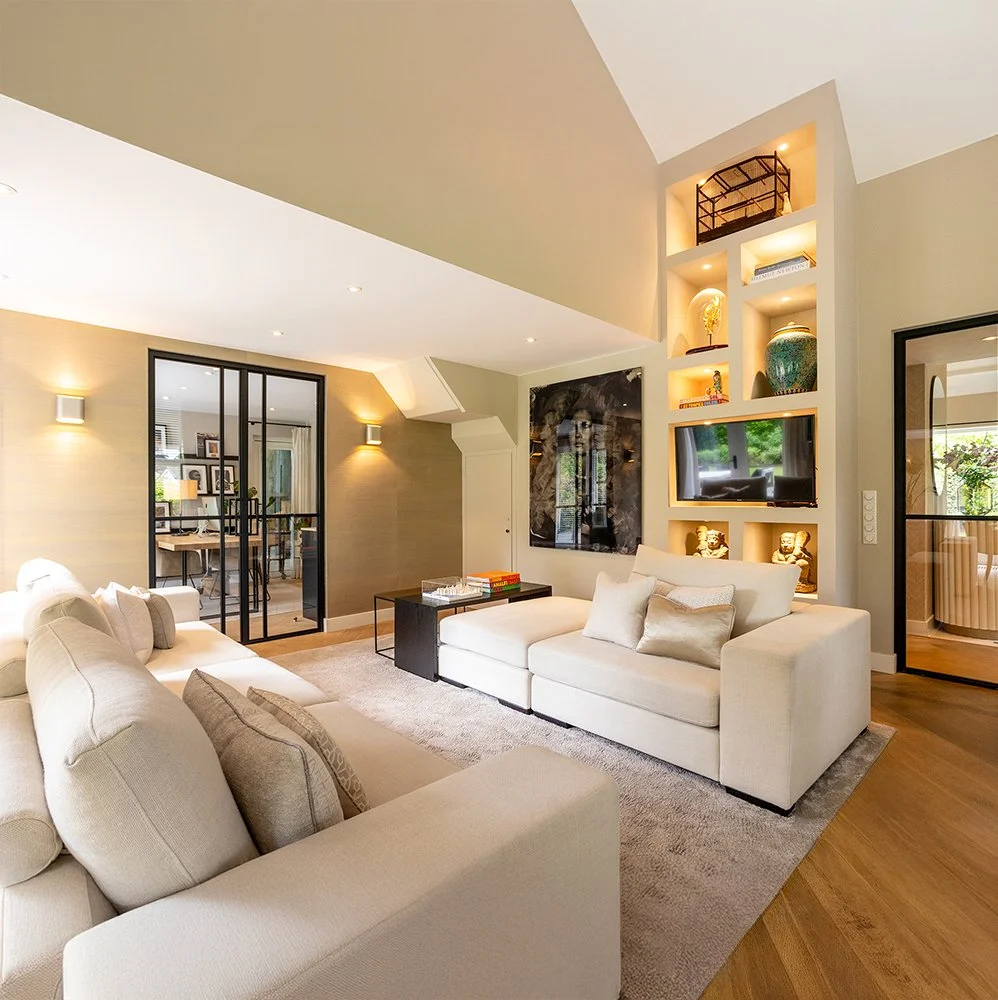 Lichte woonkamer met witte banken, ingebouwde boekenplank, televisie en decoratieve items