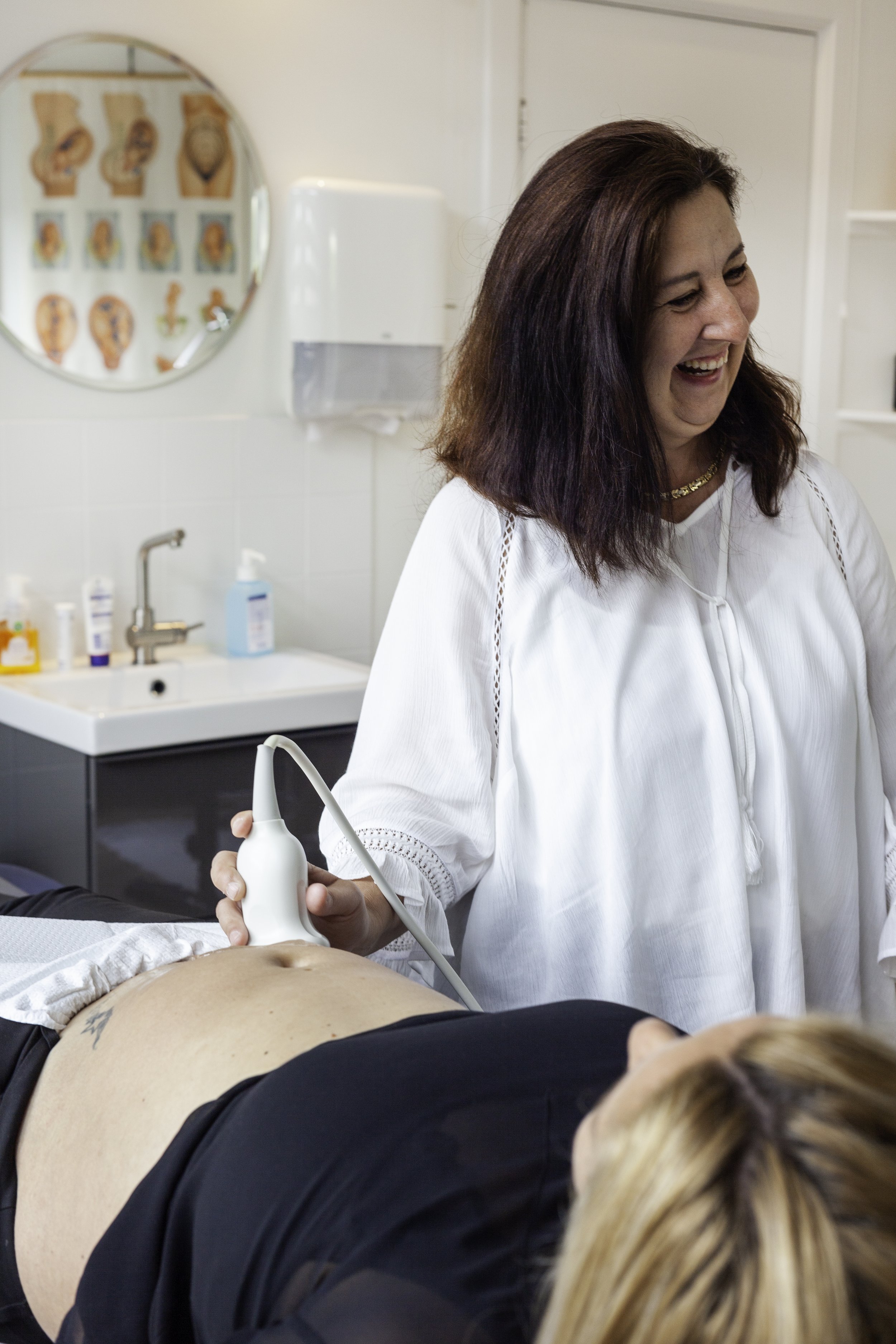 Vrouw die een echo-onderzoek uitvoert op een patiënt in een medische praktijk of kliniek.