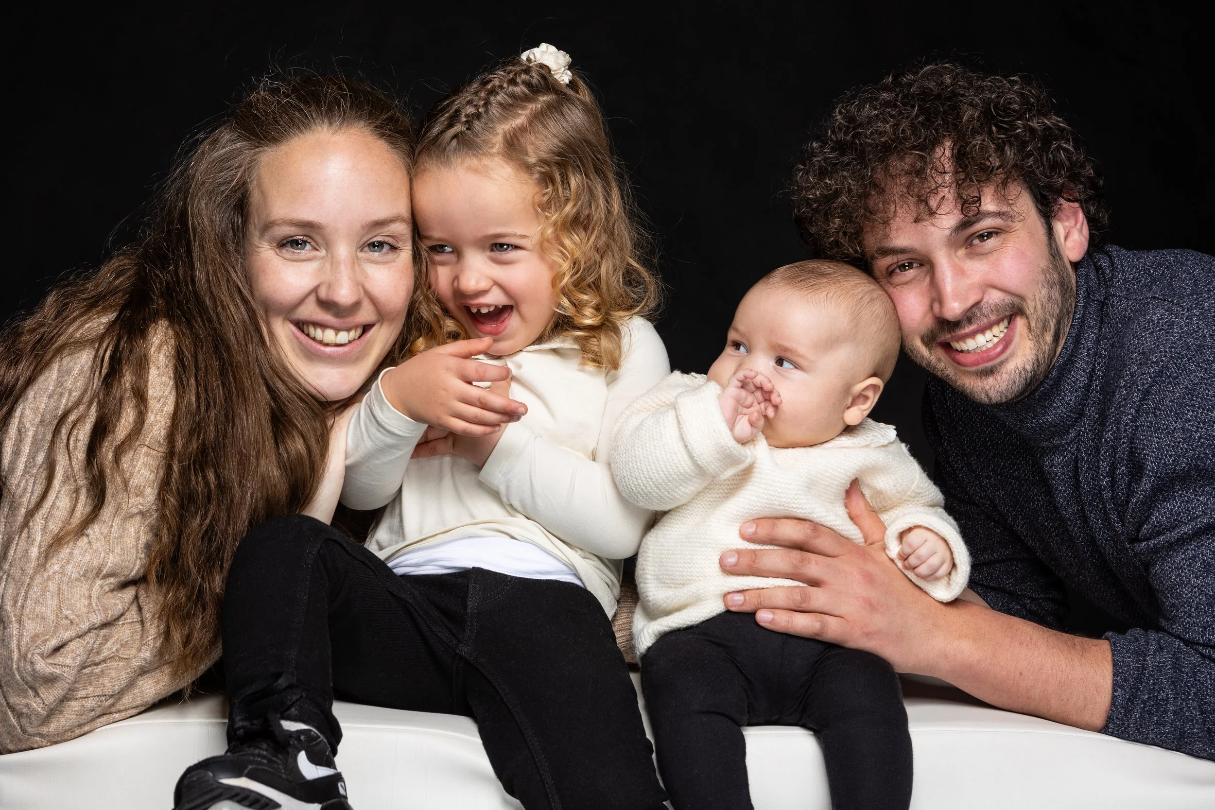 Gezin met vier mensen lachen samen op een zwarte achtergrond.