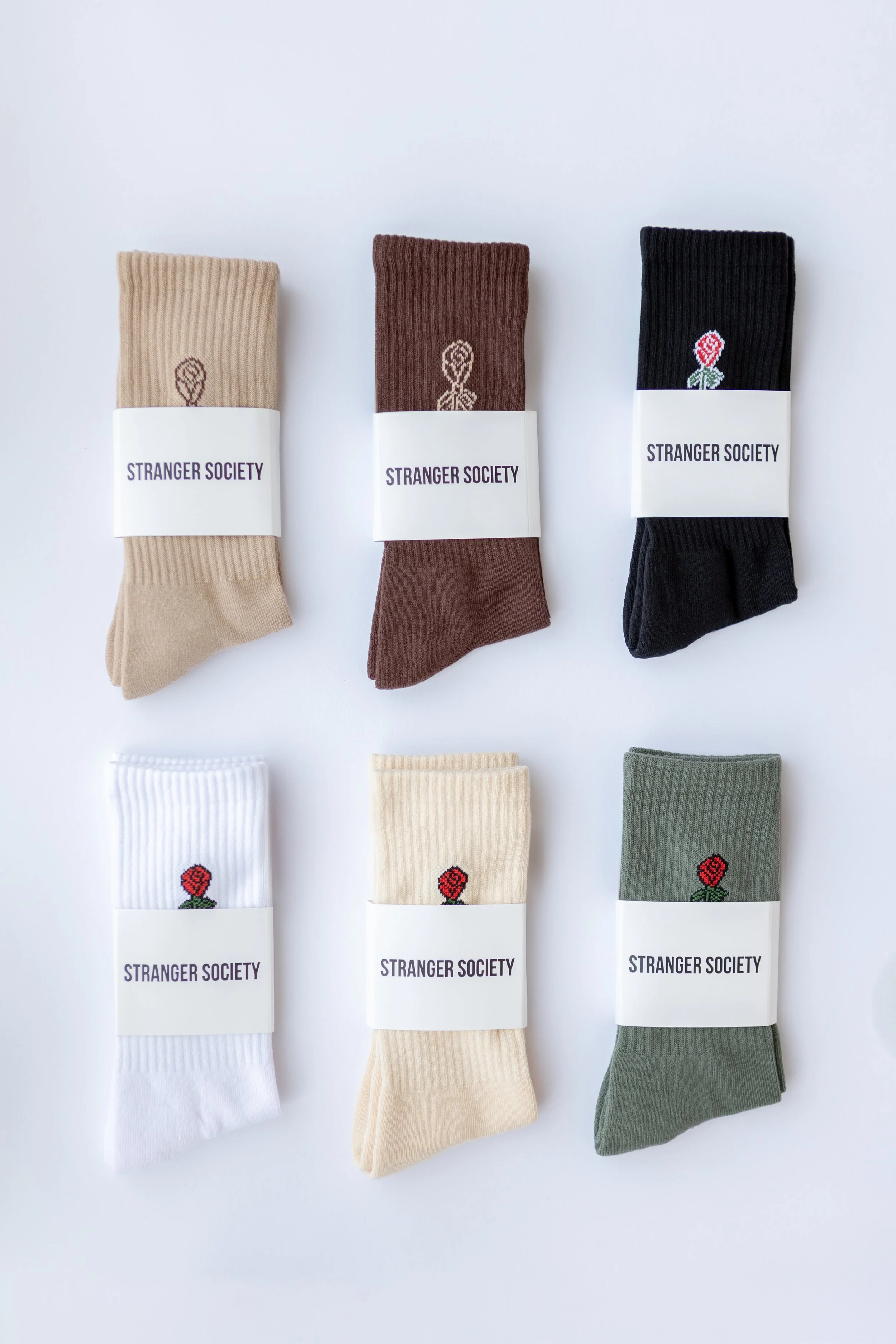 Sokken met verschillende kleuren en kleine bloemen- of hartpatronen, verpakt met 'Stranger Society' labels op een witte achtergrond.