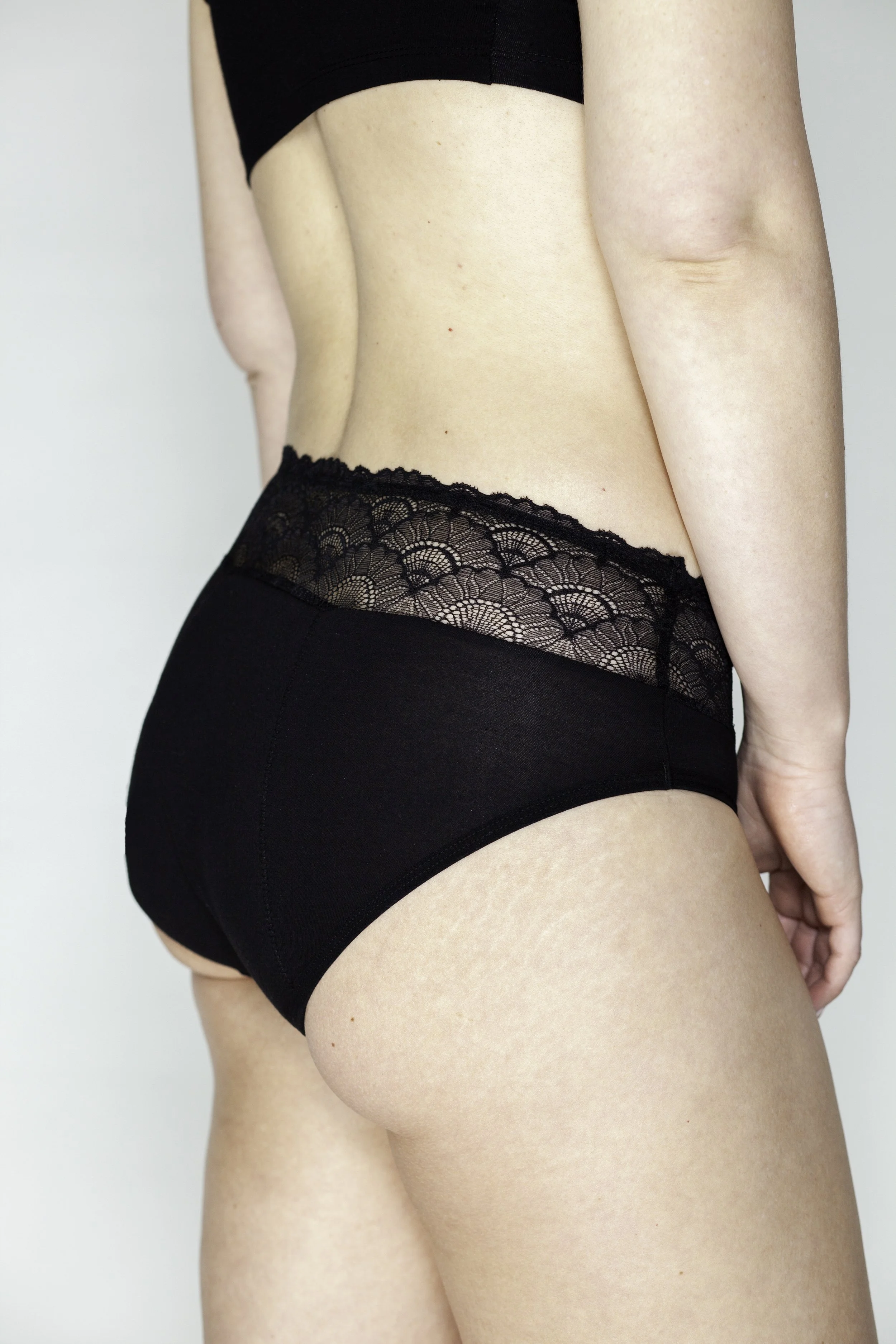 Close-up van een vrouw in zwarte ondergoed, met een kanten taille en een tight-fitting onderbroek.