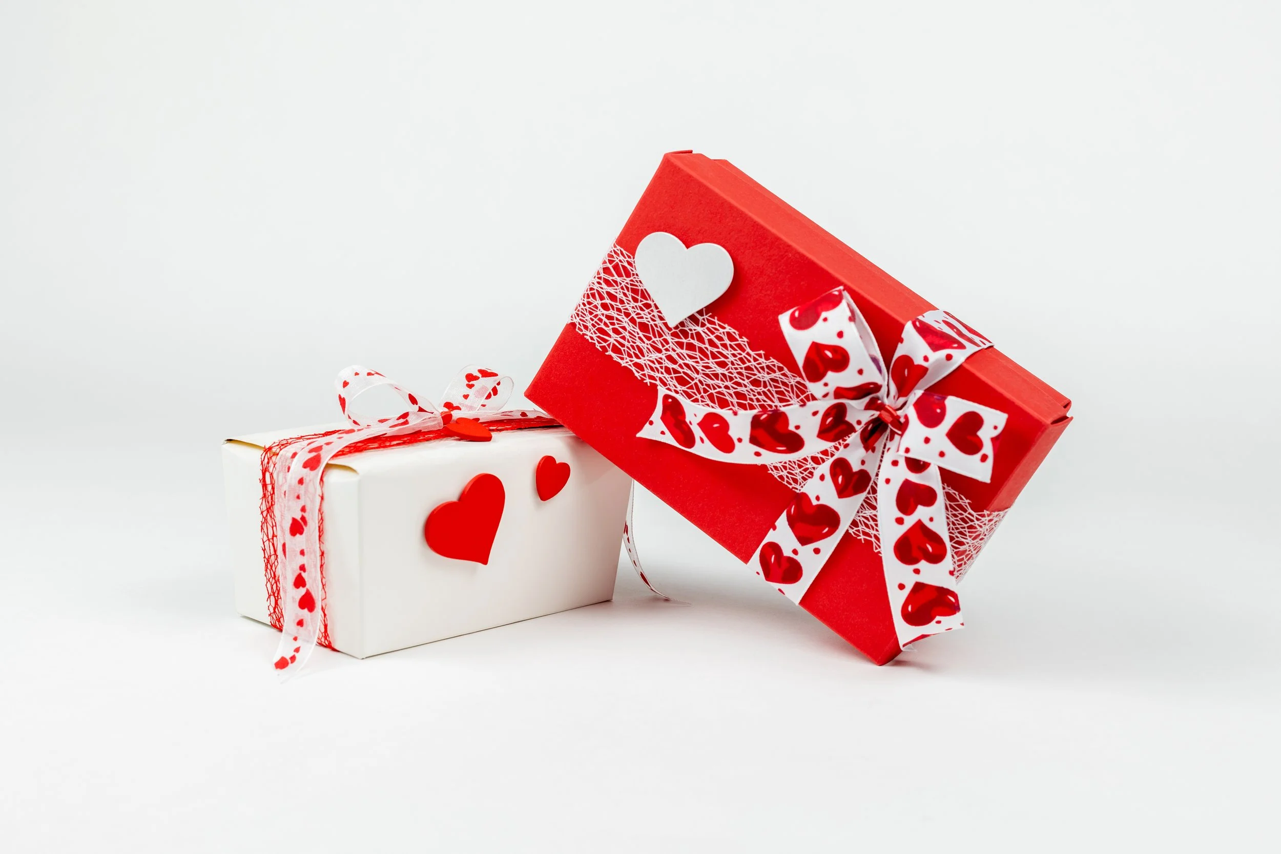 Twee cadeaubonnen met hartjes en lint op een witte achtergrond.