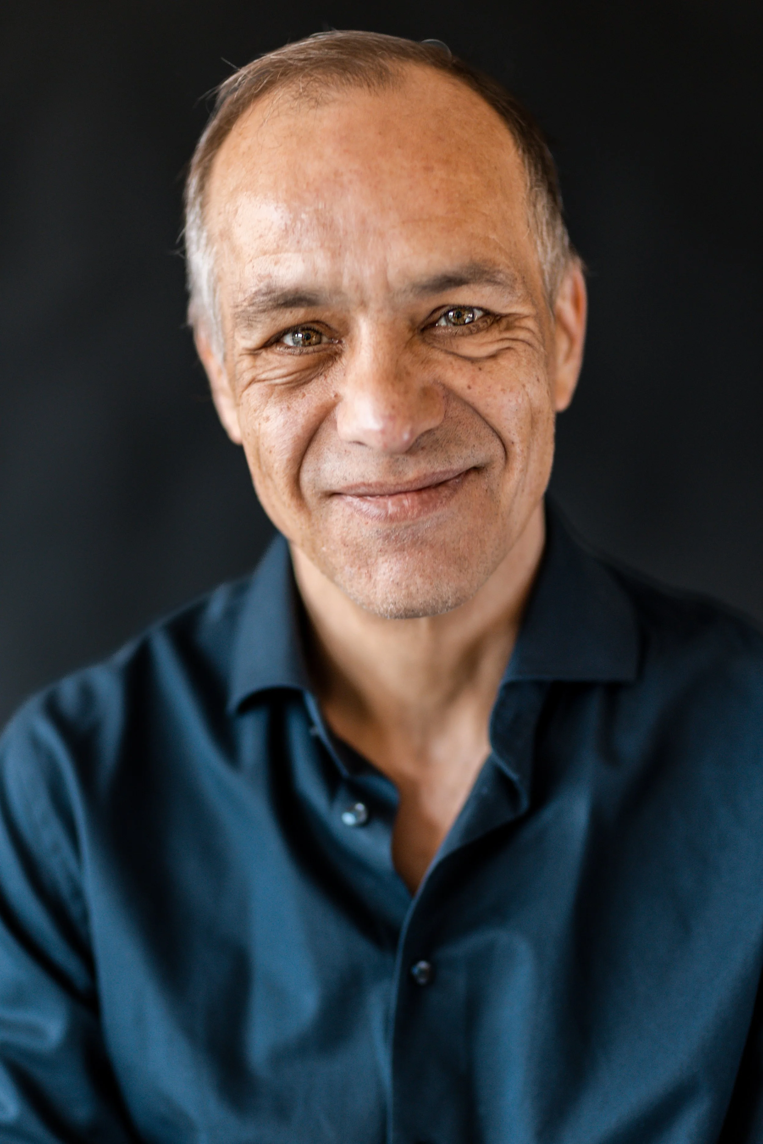 Portret van een glimlachende man met kort haar, in een donkerblauwe shirts.