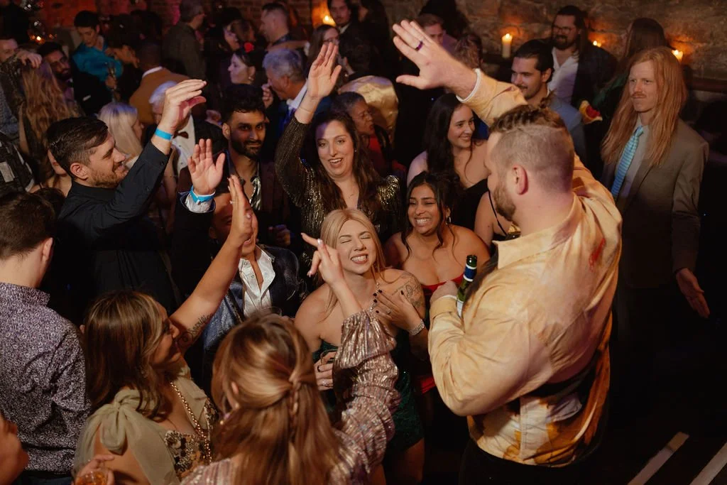 People dancing and enjoying themselves at a lively party or celebration, with some holding drinks.