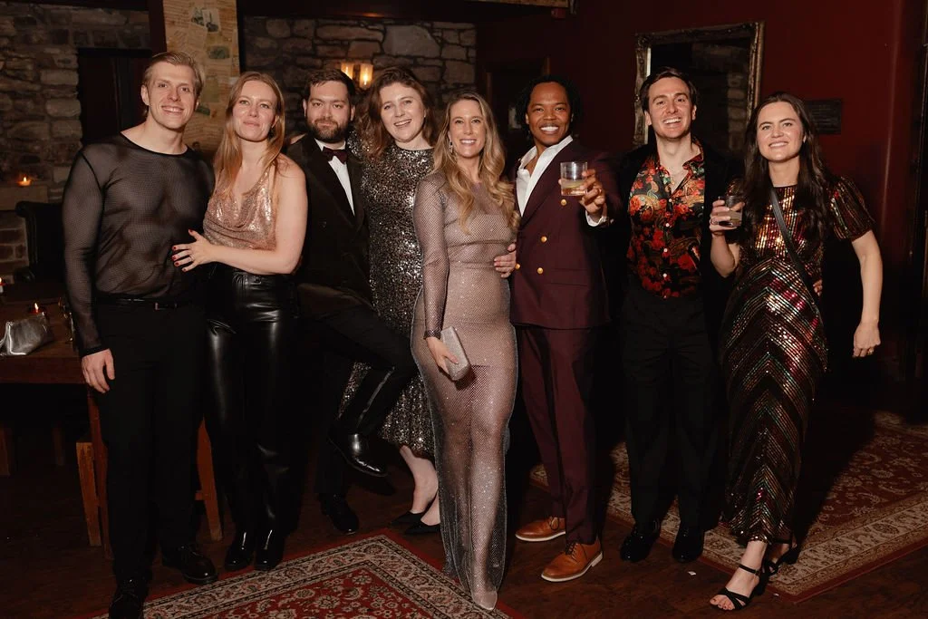 A group of friends posing together at their friends wedding after party in Edinburgh. dressed in party attire, standing together and smiling indoors at a celebration or party.