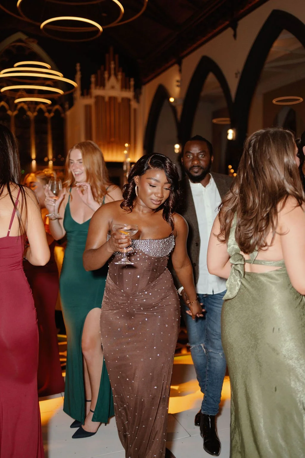 People dancing and socializing at an elegant party or wedding reception in a decorated venue with warm lighting.