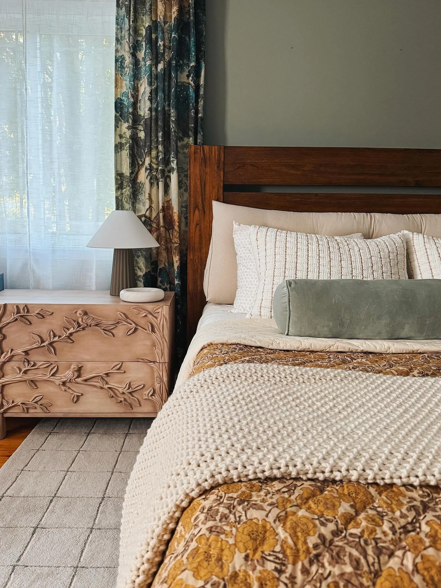 A case for the space that feels rich, layered, and storied. 

A beautiful primary bedroom refresh with green washed walls, carved wood nightstands, printed curtains, and new tonal textures throughout the rug and bedding. 

Inquire to learn more about