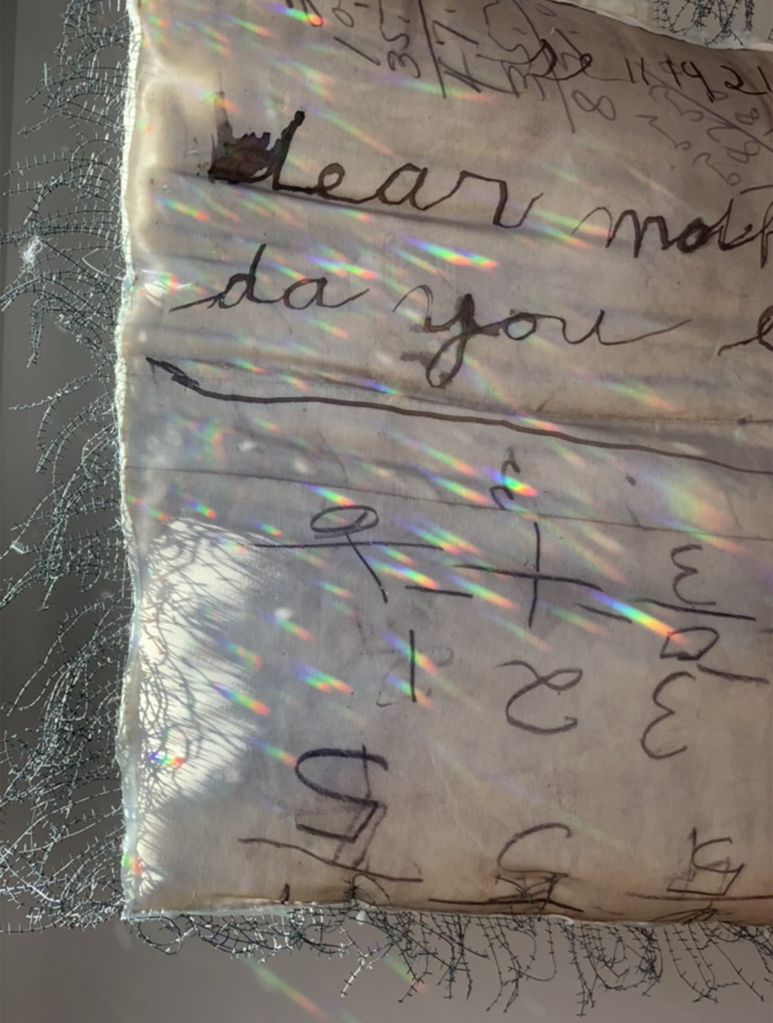 A handwritten note on a piece of paper with rainbow light reflections and spider webs on the edges. The note says, 'Learn more' and 'day you', with some additional, less clear words.