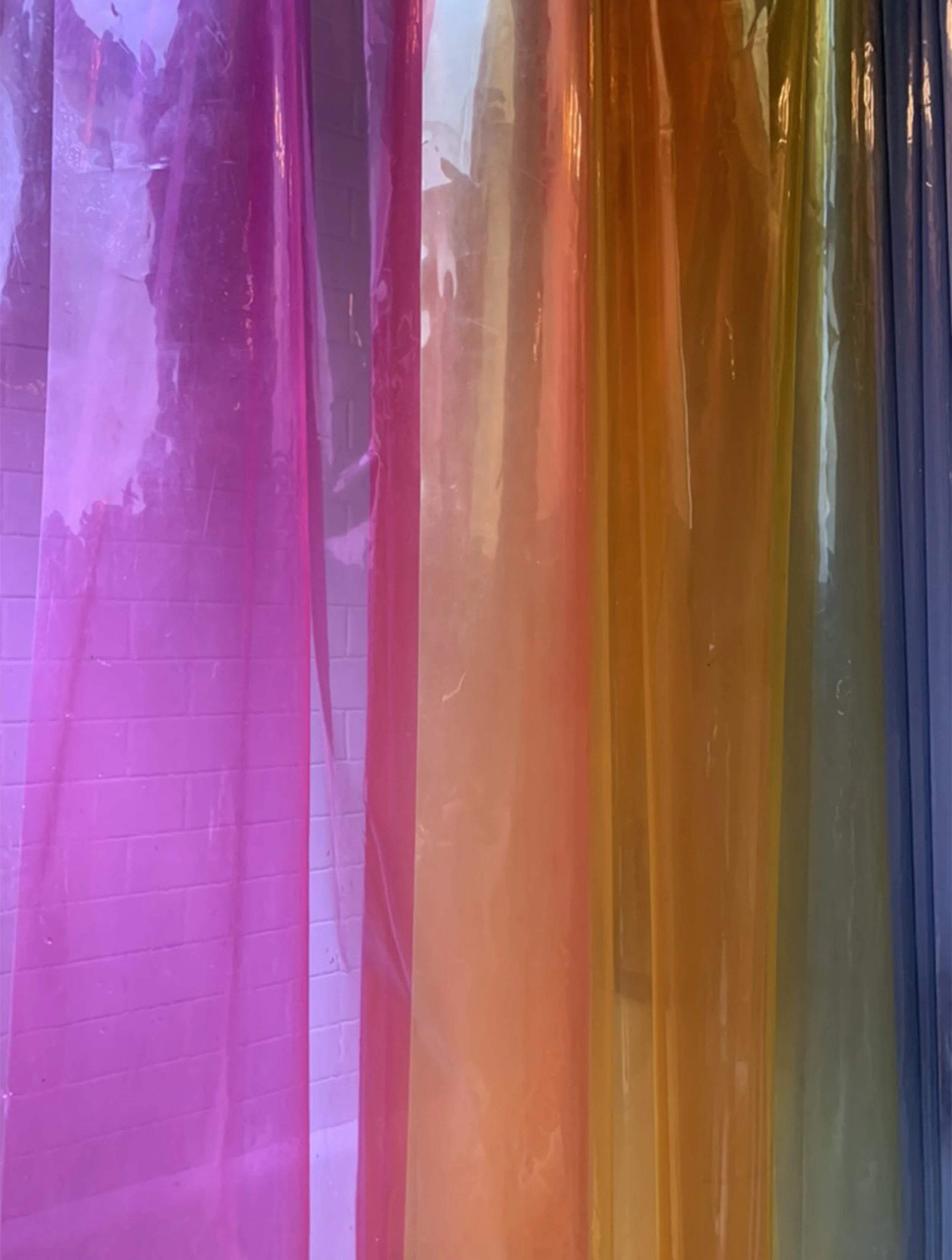 Colorful, semi-transparent hanging plastic or fabric strips in pink, orange, yellow, green, and blue.