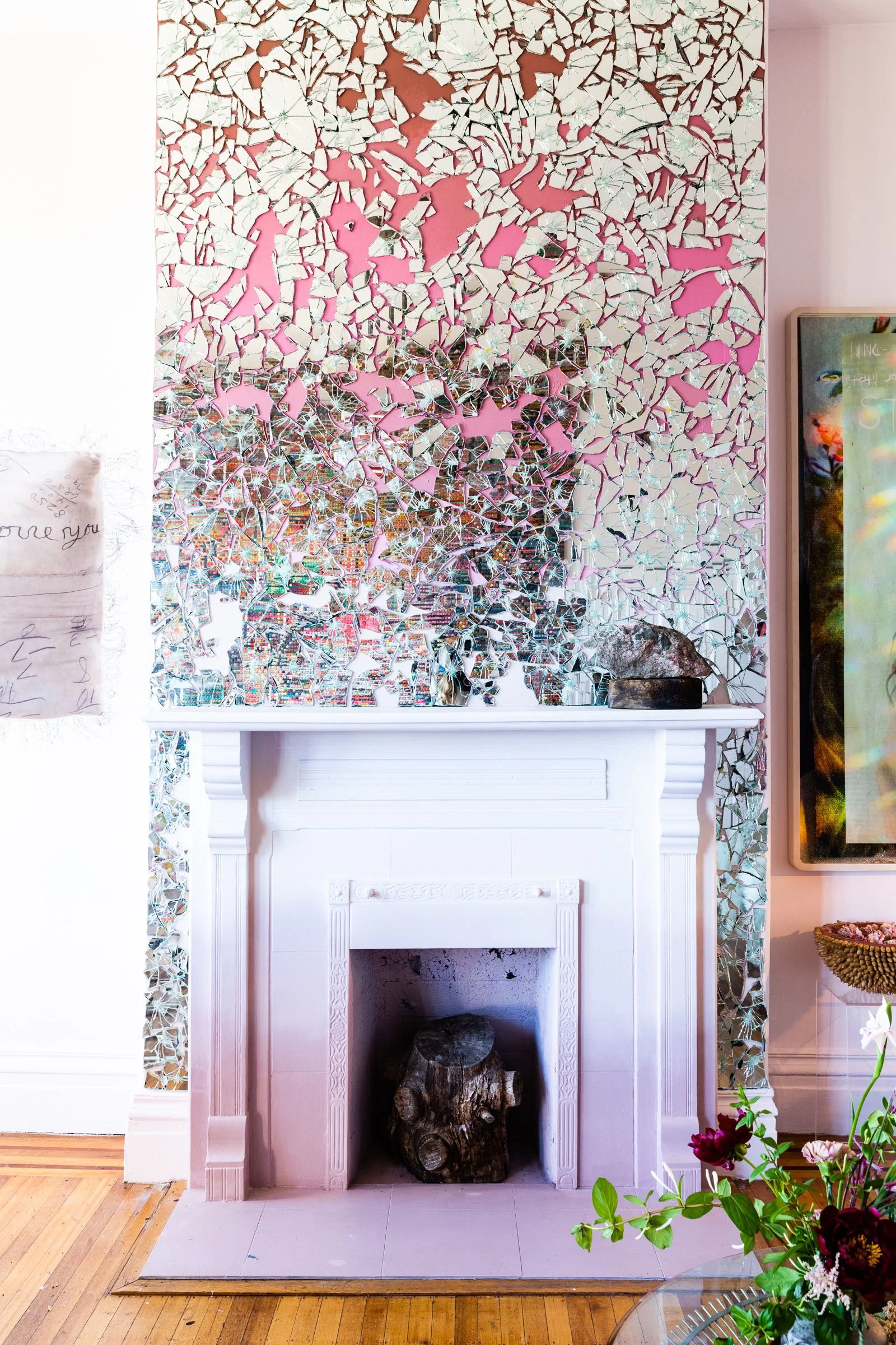 Decorative mirror mosaic wall above a white fireplace with a wooden log inside.