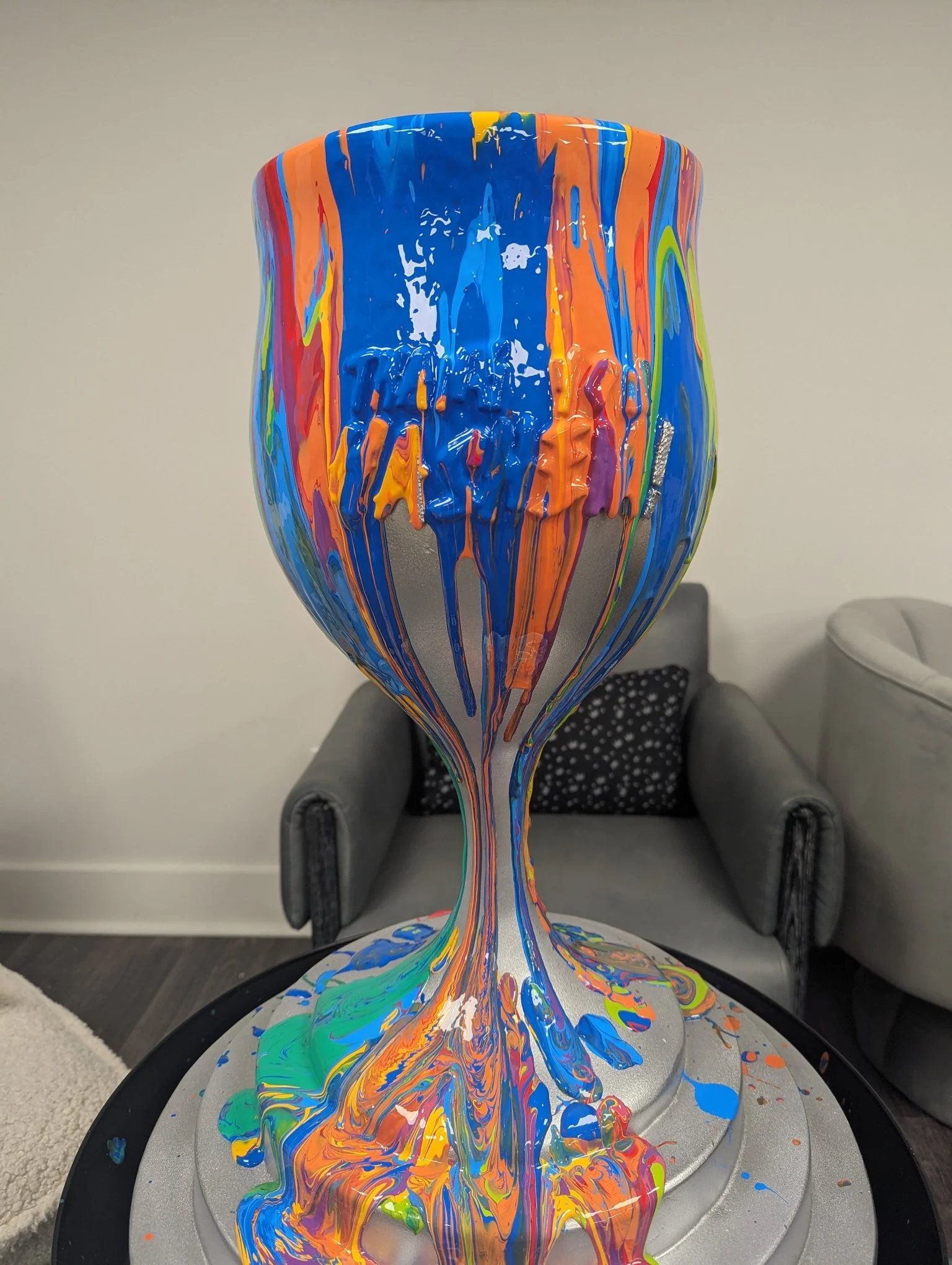 Overflowing Blessings kiddush cup sculpture by Yitzchok Moully — colorful abstract paint splatter on metallic base, Jewish Judaica art in home setting