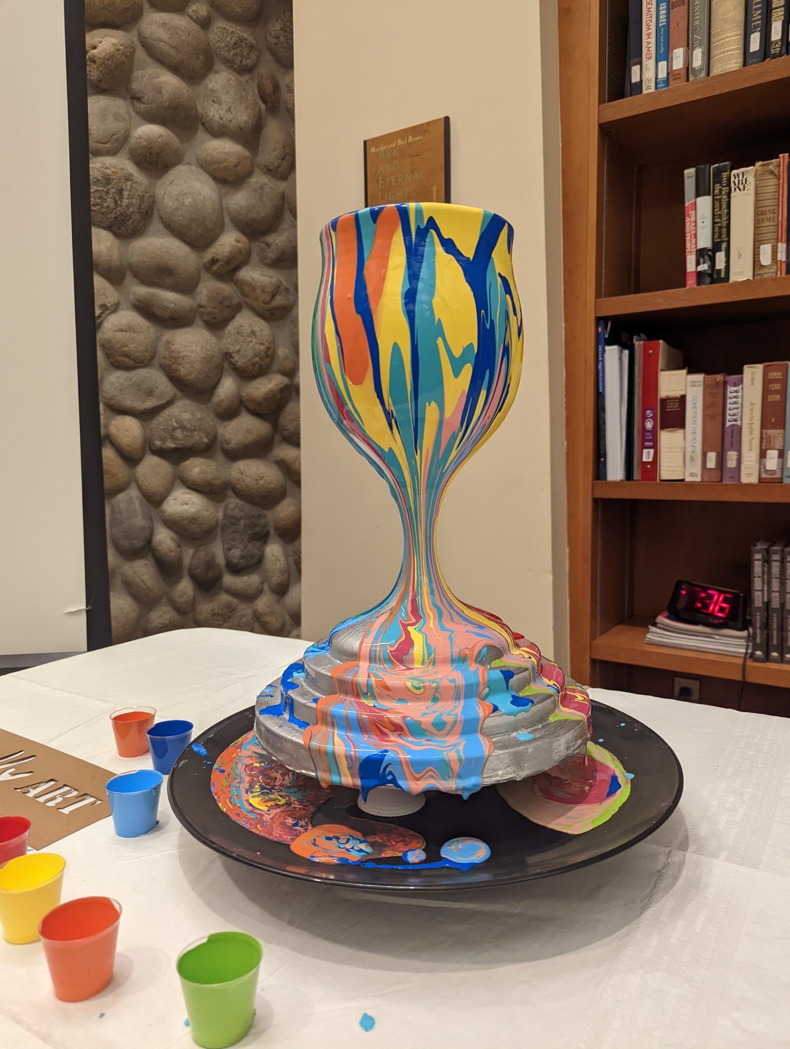 Colorful Hanukkiah menorah sculpture by Yitzchok Moully — decorative Jewish art piece on display table with colorful cups