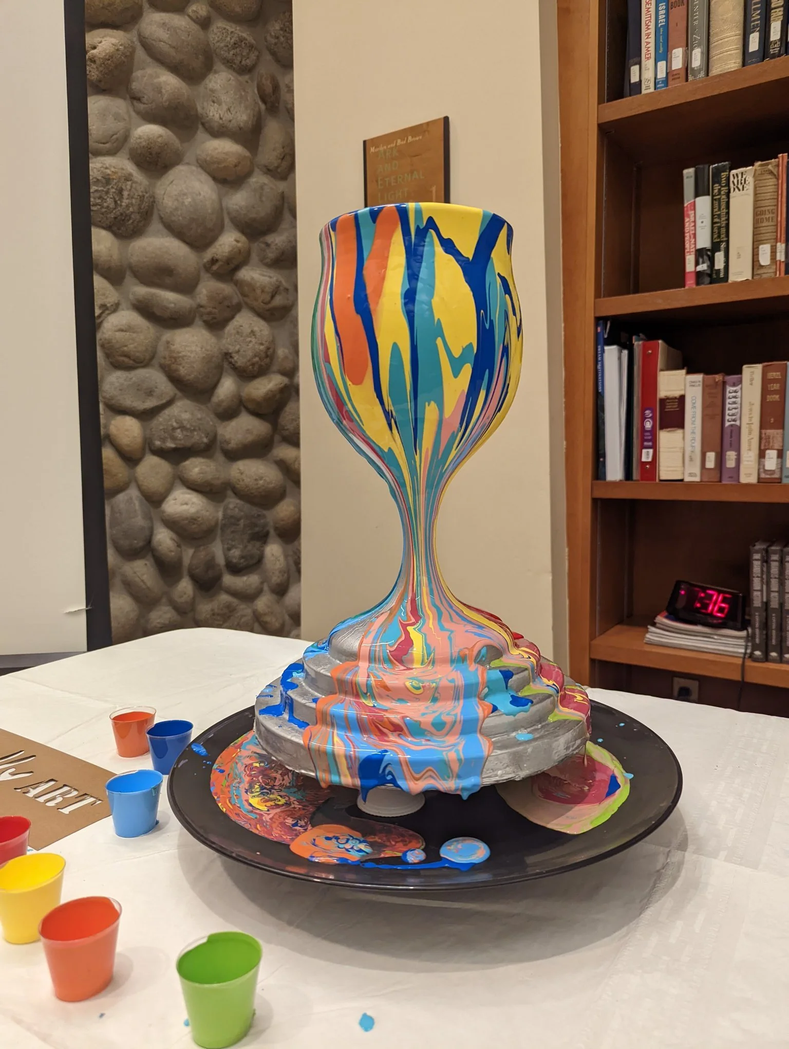 Colorful Hanukkiah menorah sculpture by Yitzchok Moully — decorative Jewish art piece on display table with colorful cups
