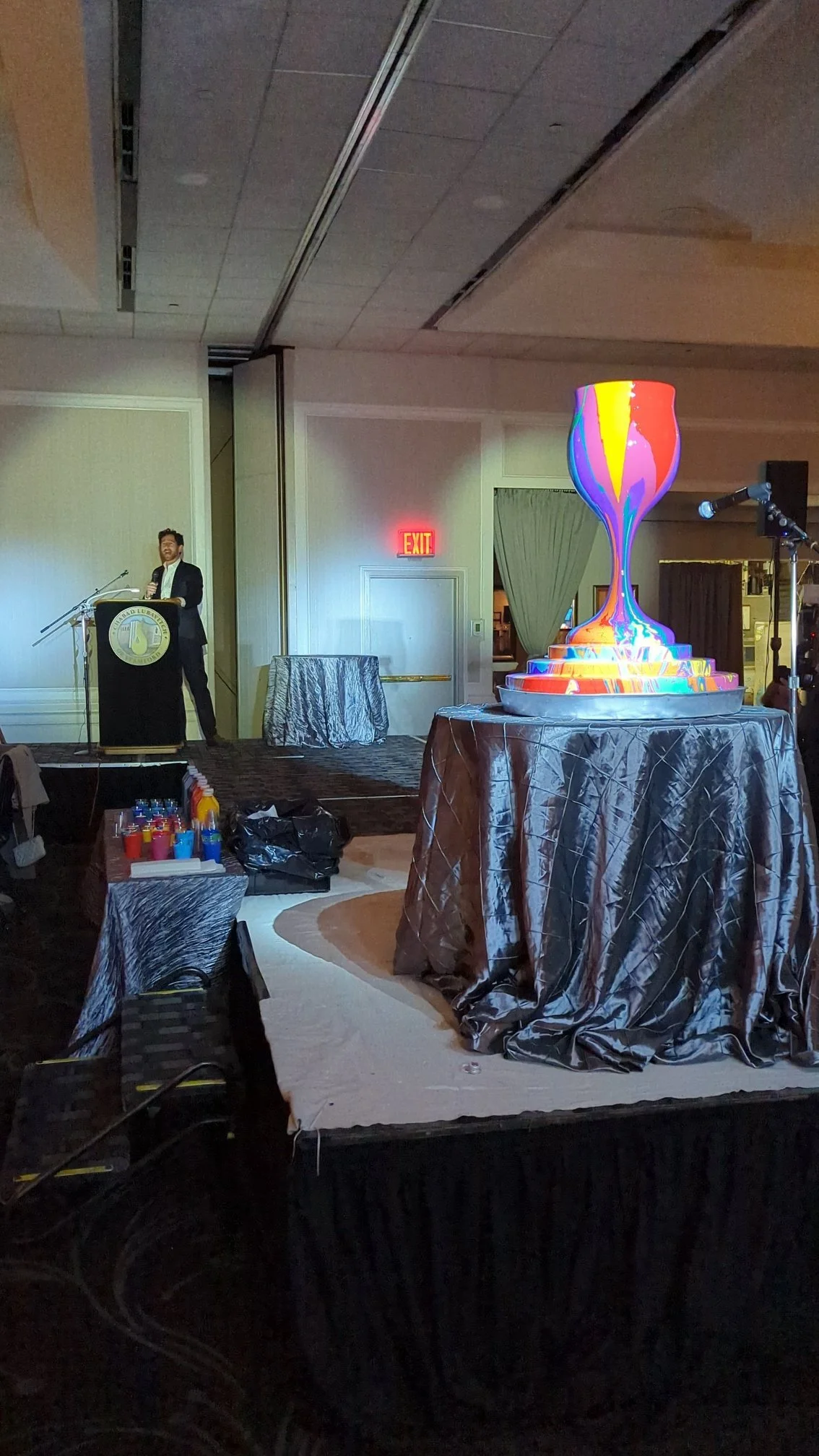 Overflowing Blessings illuminated kiddush cup sculpture by Yitzchok Moully — colorful Jewish art centerpiece at indoor gala event
