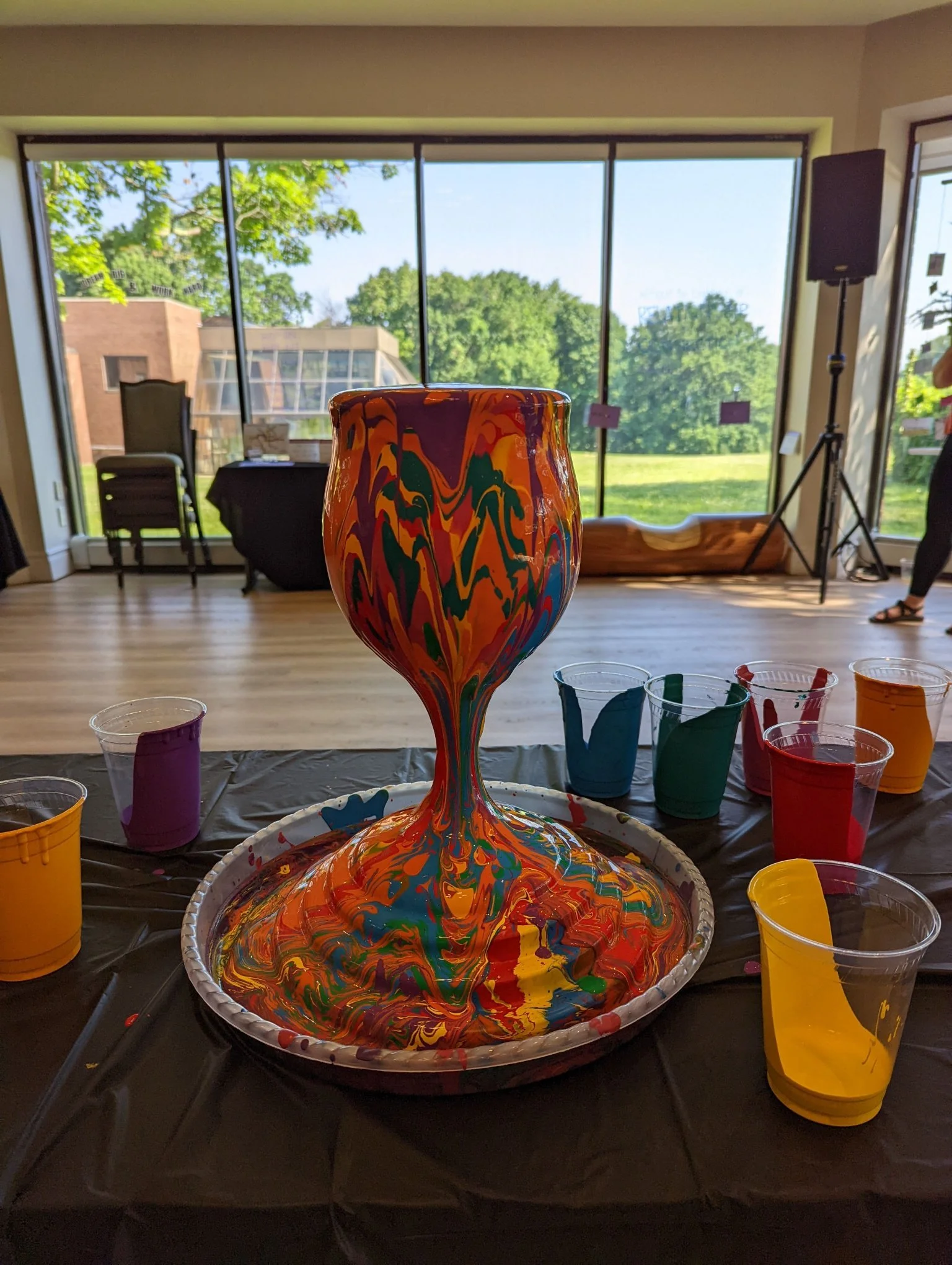 Colorful marbled paint-pour art activity by Yitzchok Moully — interactive Jewish art workshop with paint cups and kiddush cup-shaped canvas