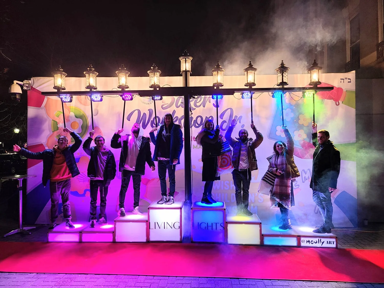 A community gathered around a glowing public menorah installation