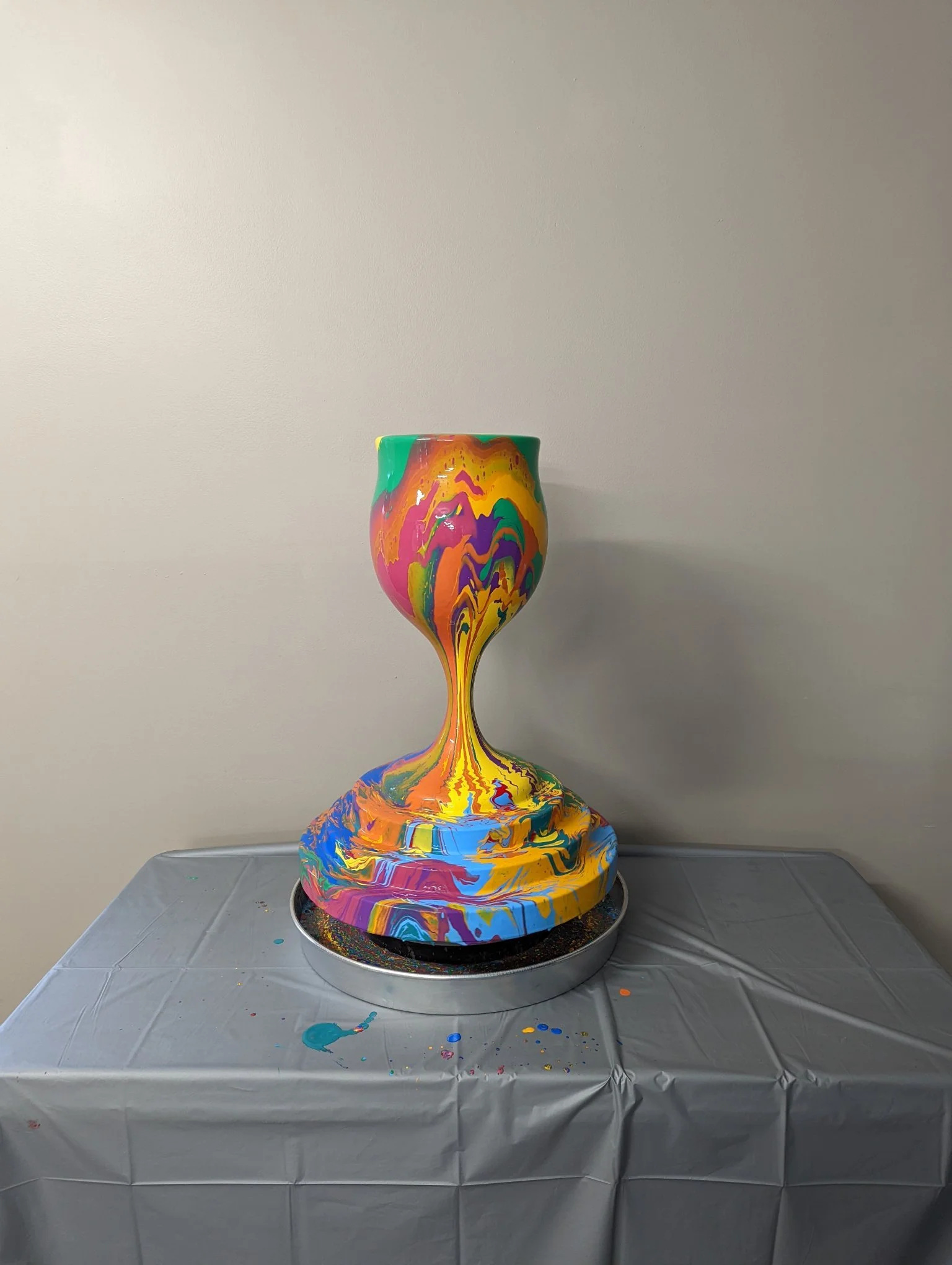 Overflowing Blessings kiddush cup by Yitzchok Moully — colorful paint-pour Jewish Judaica art sculpture on silver display table
