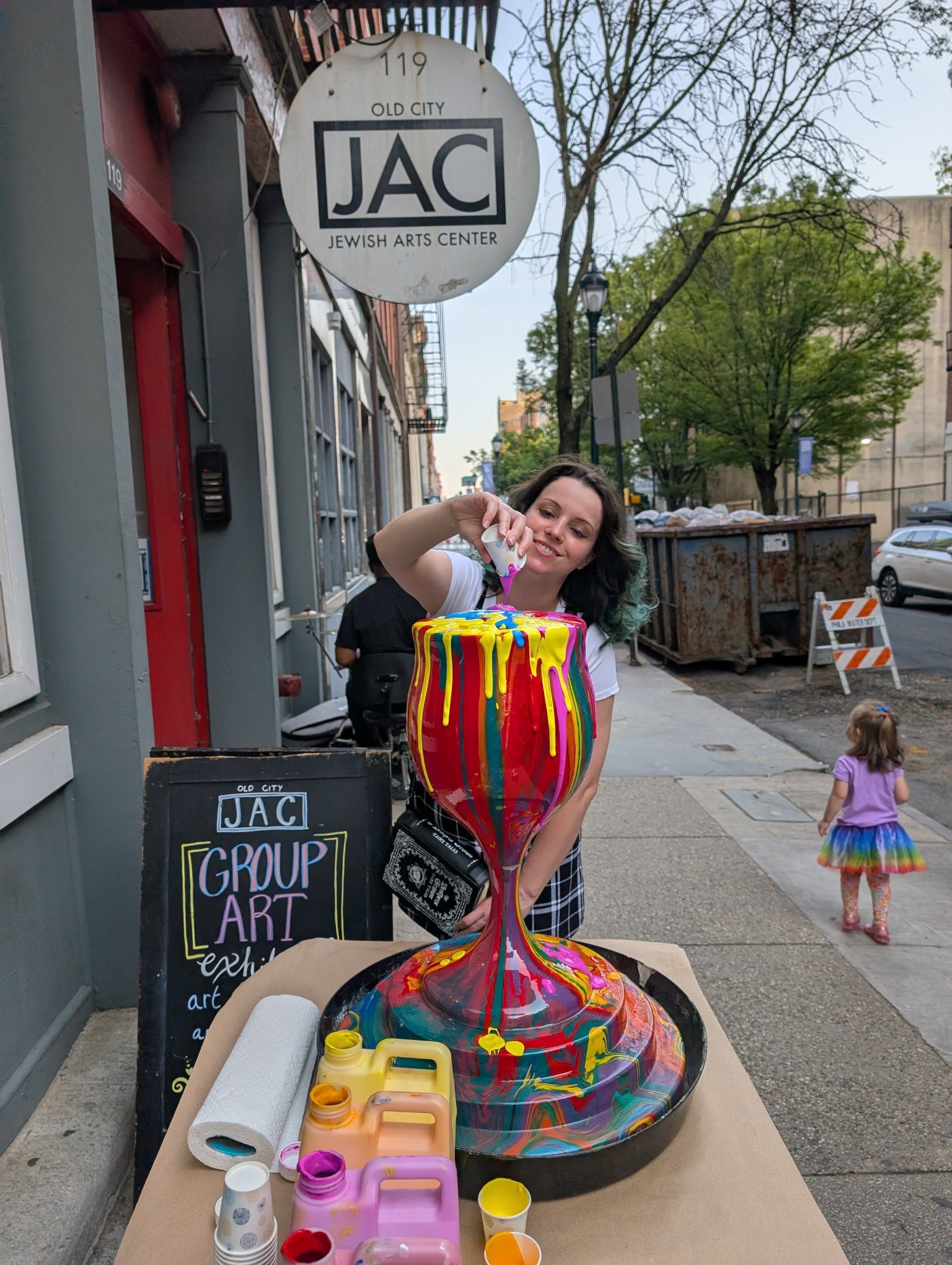 Paint-pour participant creating Overflowing Blessings kiddush cup at Jewish Arts Center Group Art outdoor event by Yitzchok Moully