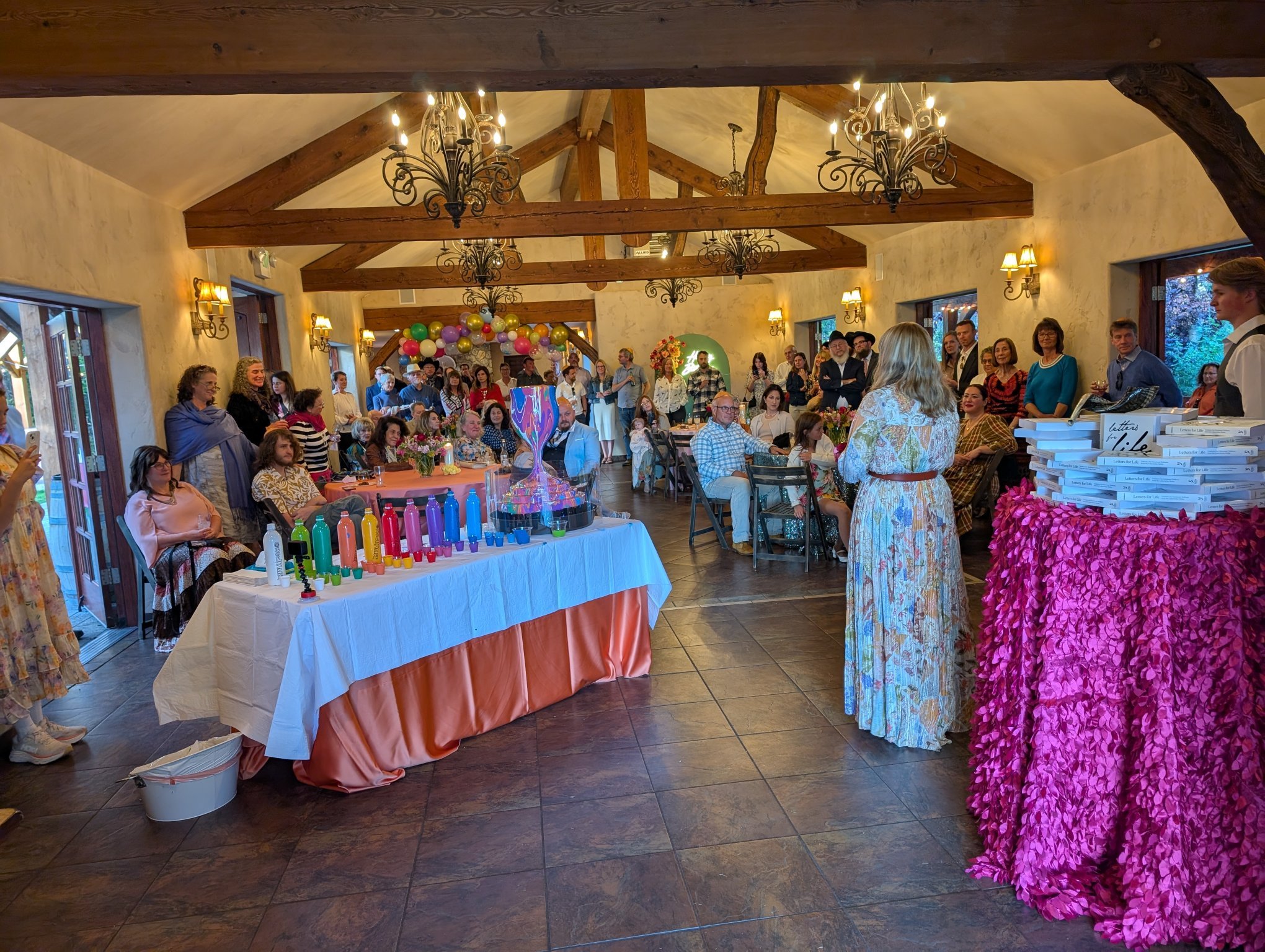 Guests at Jewish community gala event featuring Yitzchok Moully art — celebration dinner in rustic venue with chandeliers and decorated tables