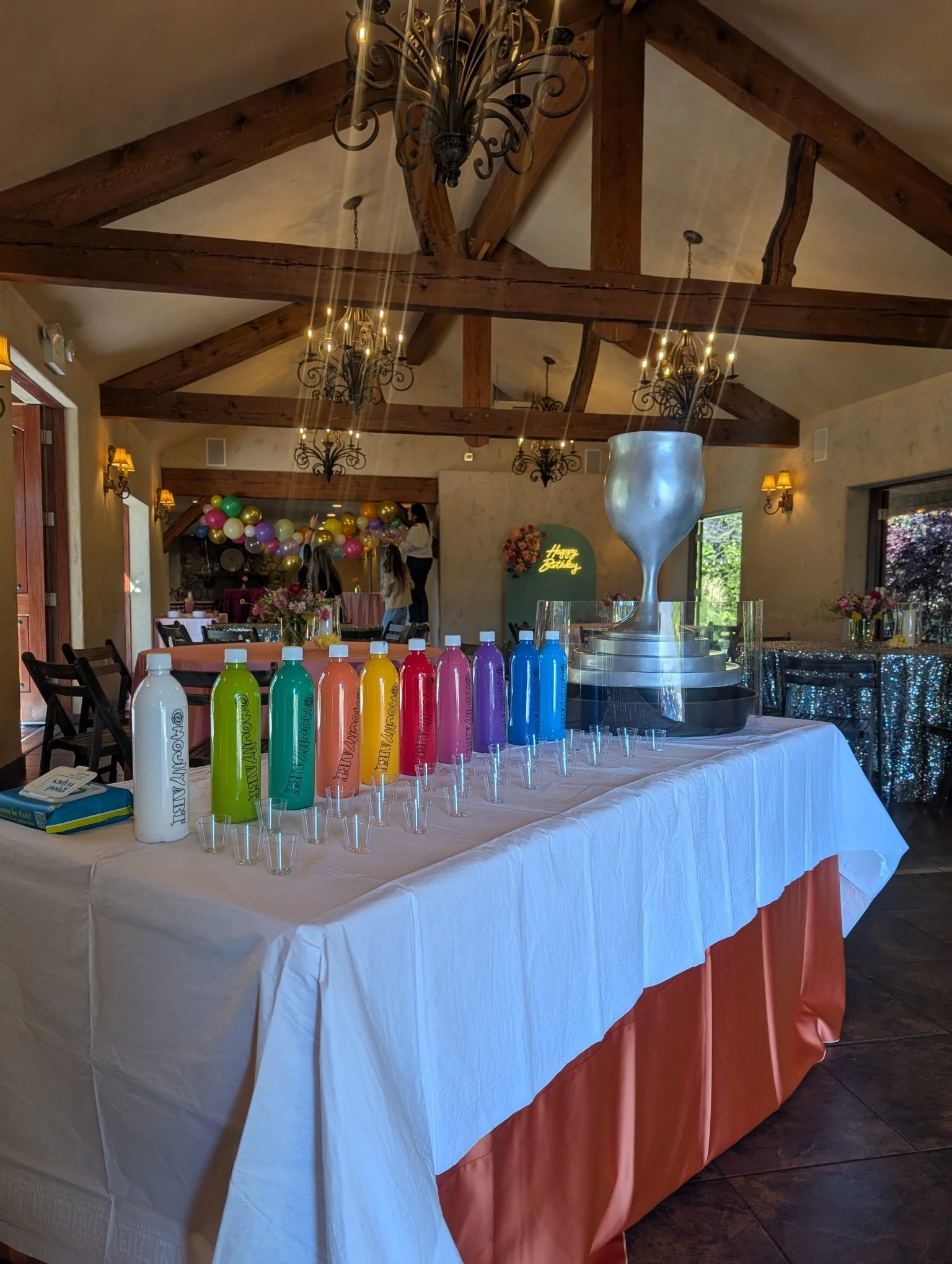 Overflowing Blessings art display at Jewish gala event by Yitzchok Moully — colorful paint bottles and silver Judaica trophy centerpiece on decorated celebration table