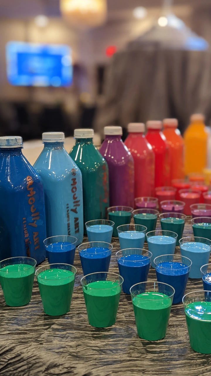 Colorful paint bottles in rainbow spectrum — art supplies for Yitzchok Moully’s Jewish public art and community workshop projects