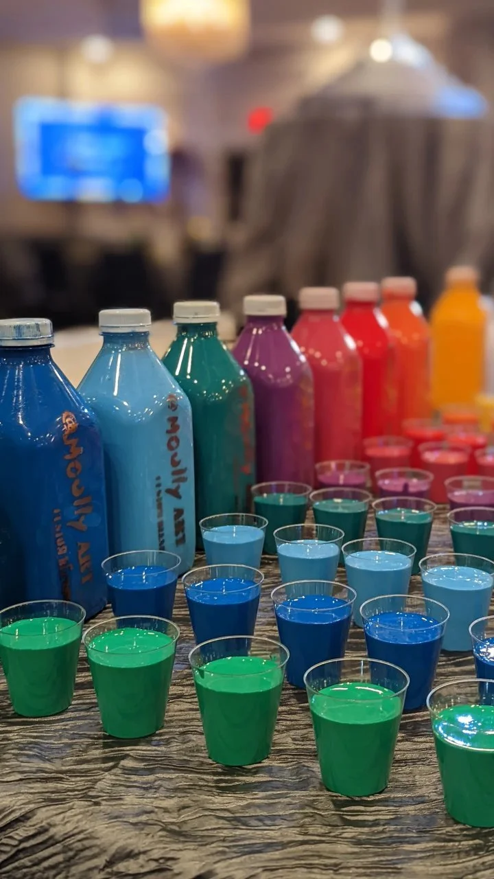 Colorful paint bottles in rainbow spectrum — art supplies for Yitzchok Moully’s Jewish public art and community workshop projects