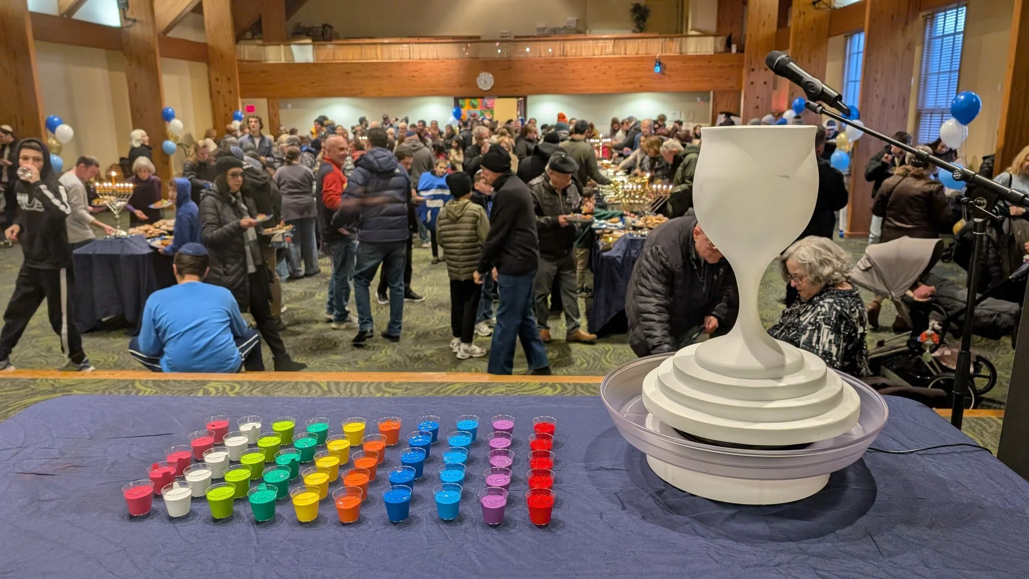 Hanukkah public candle lighting event featuring drip-paint menorah by Yitzchok Moully — community celebration with colorful Judaica and traditional kiddush cup
