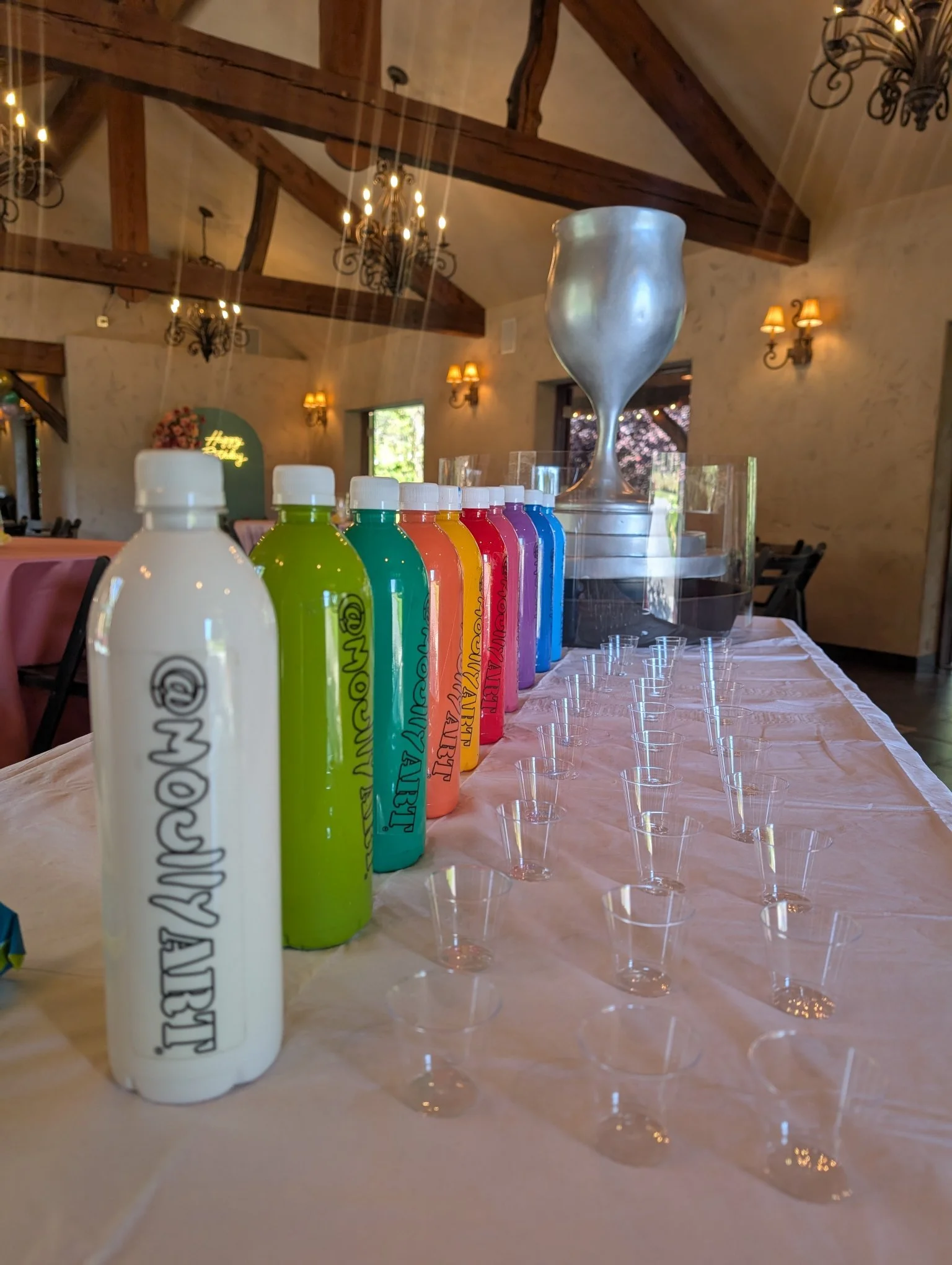 Paint bottle setup for Yitzchok Moully’s interactive paint-pour event — Overflowing Blessings art supplies at Jewish celebration, decorated venue