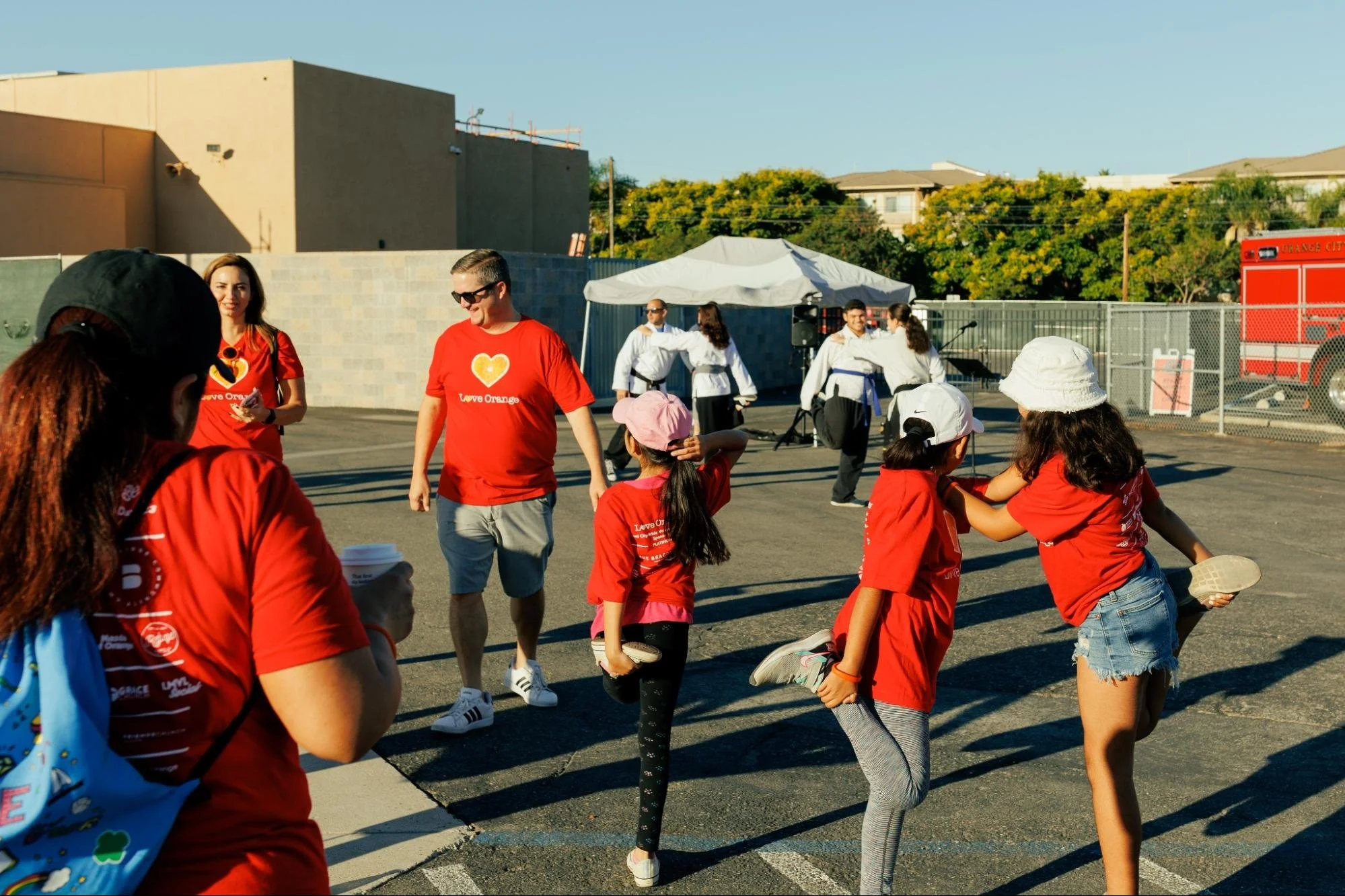    Volunteers of all ages get warmed up by performing stretches led by the martial artists from Pakua OC.   