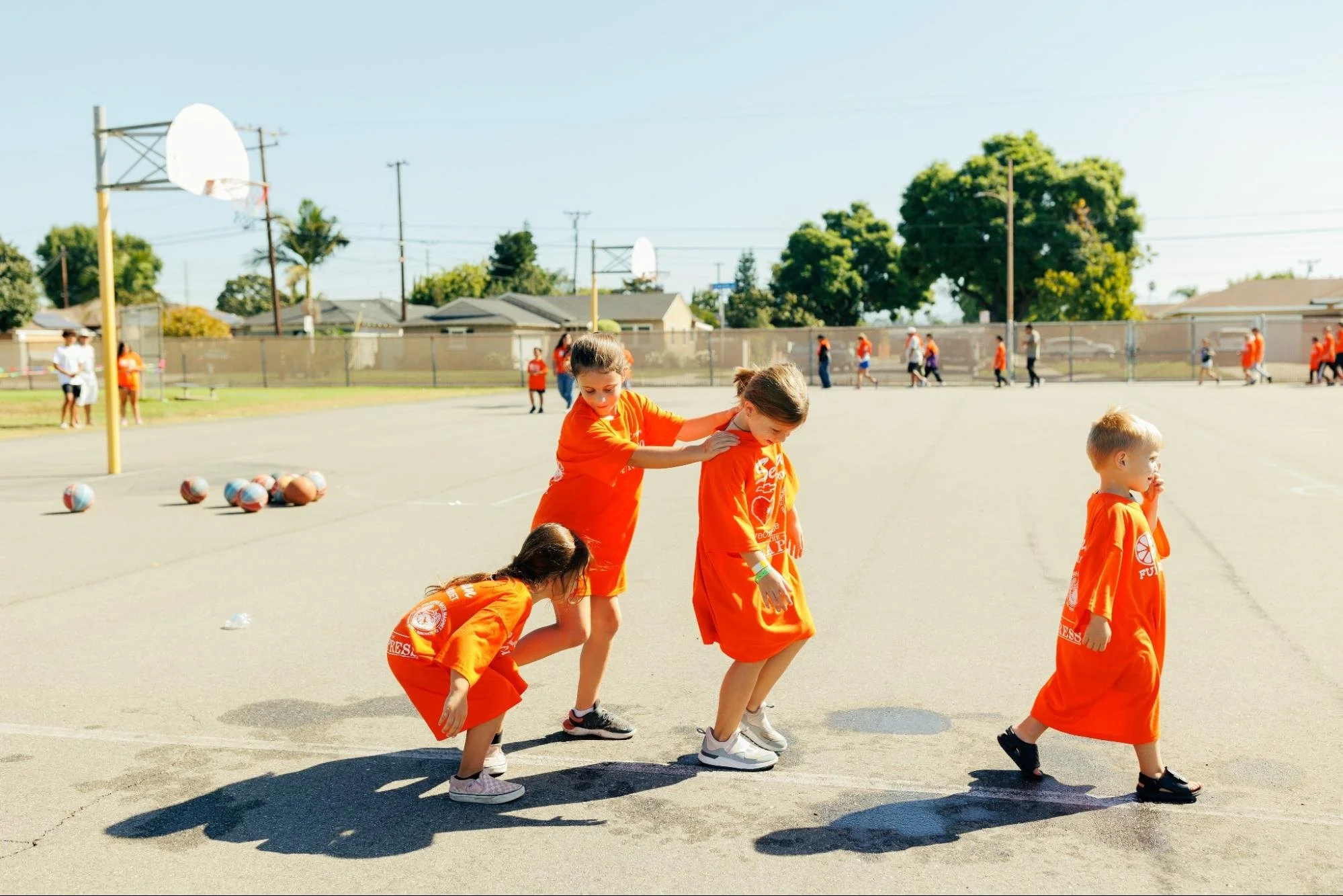    Kids in oversized Fun Run T-shirts play Follow the Leader around the basketball court.   