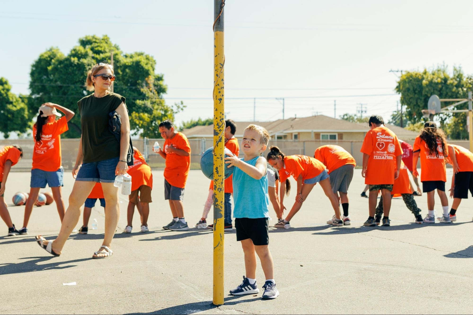    The Fun Run event is an event for everyone. A young boy entertains himself through a solo round of tetherball while the runners stretch behind him.   